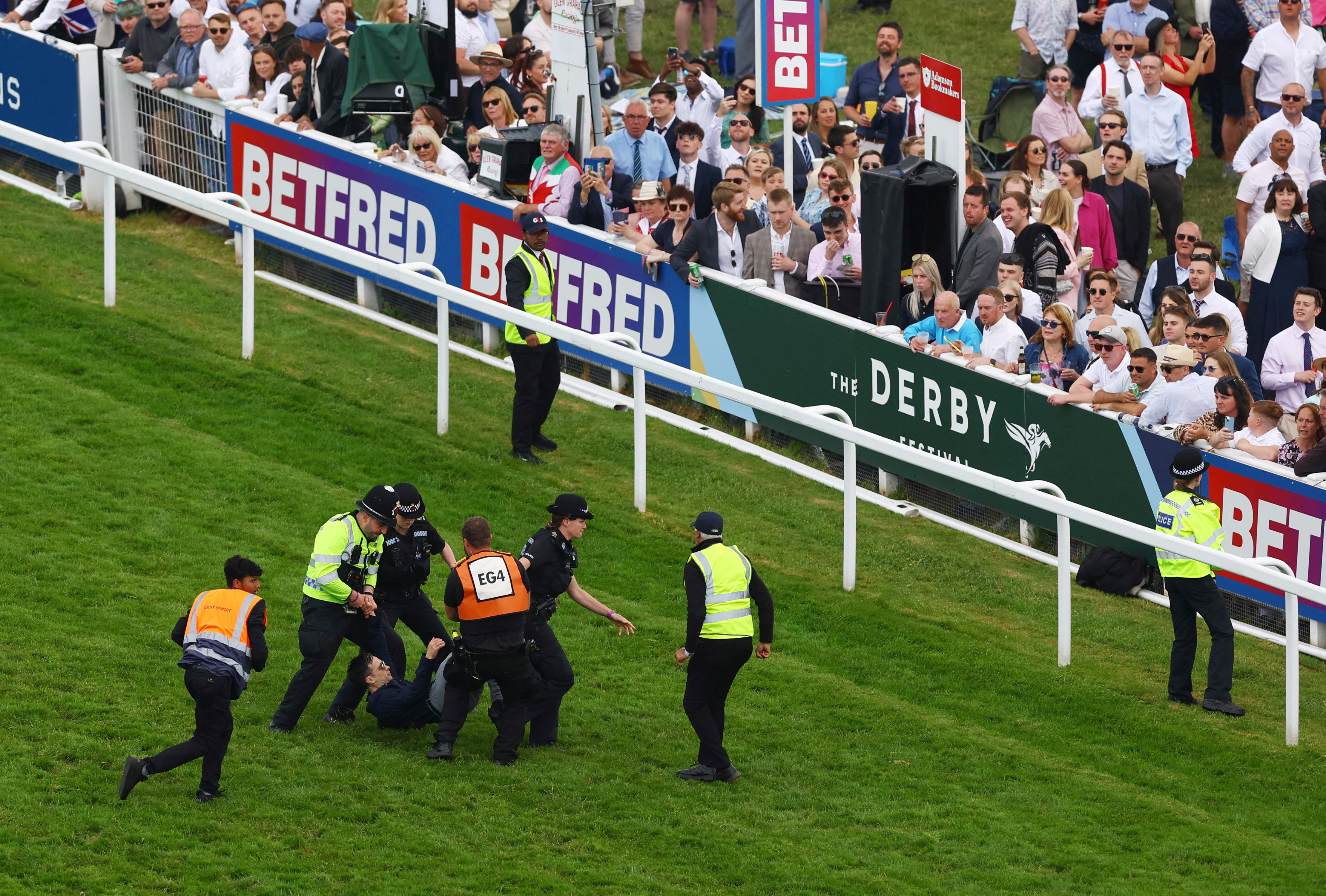 Horse Racing - Epsom Derby Festival - Epsom Downs Racecourse, Epsom, Britain - June 3, 2023 General view as a protestor is removed from the race track by police officers during the 13:30 Betfred Derby Action Images via Reuters/Matthew Childs