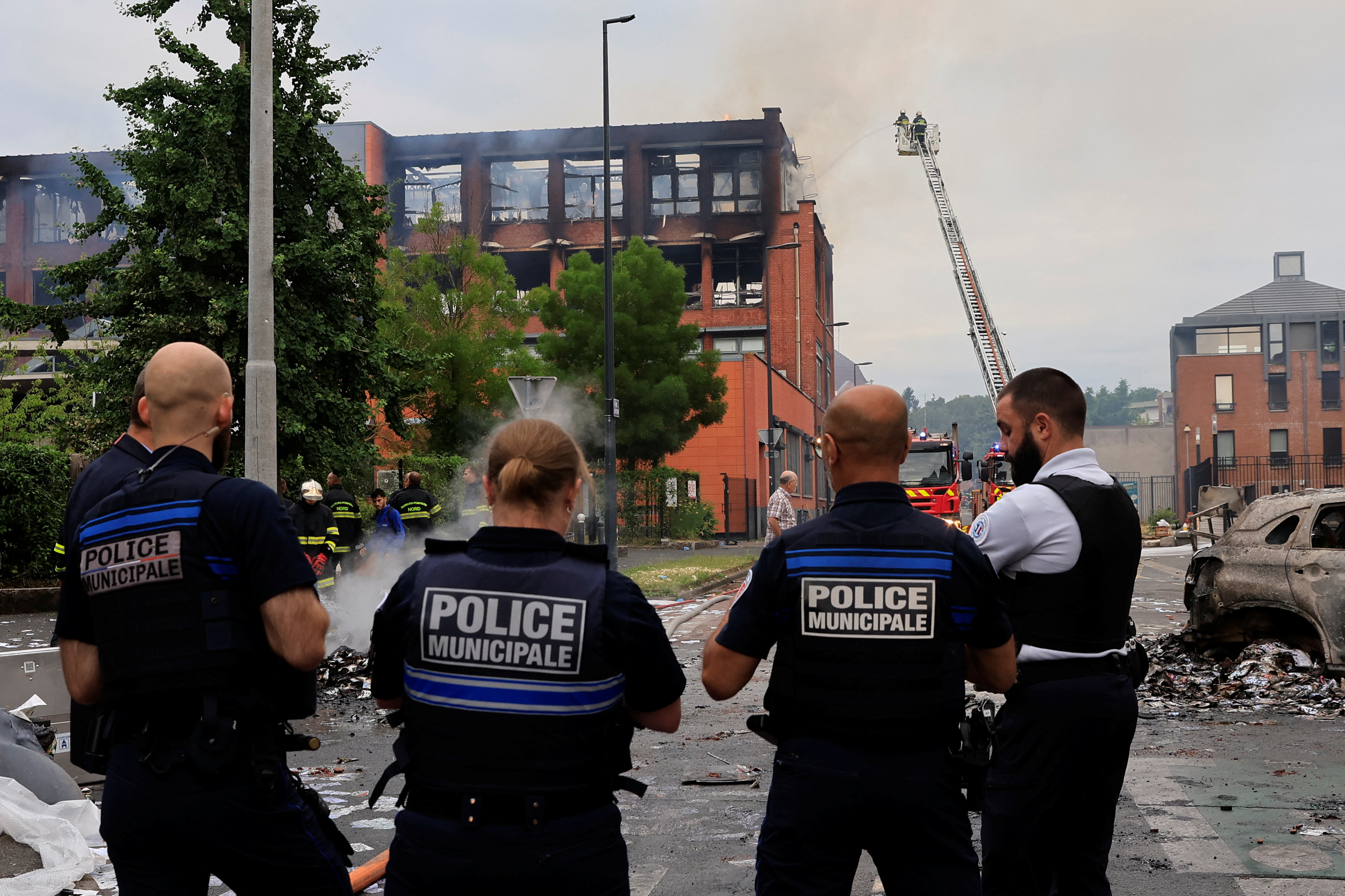 French police stand in front of a building of the Tessi group, burnt during night clashes between protesters and police, following the death of Nahel, a 17-year-old teenager killed by a French police officer in Nanterre during a traffic stop, at the Alma district in Roubaix, northern France, June 30, 2023. REUTERS/Pascal Rossignol