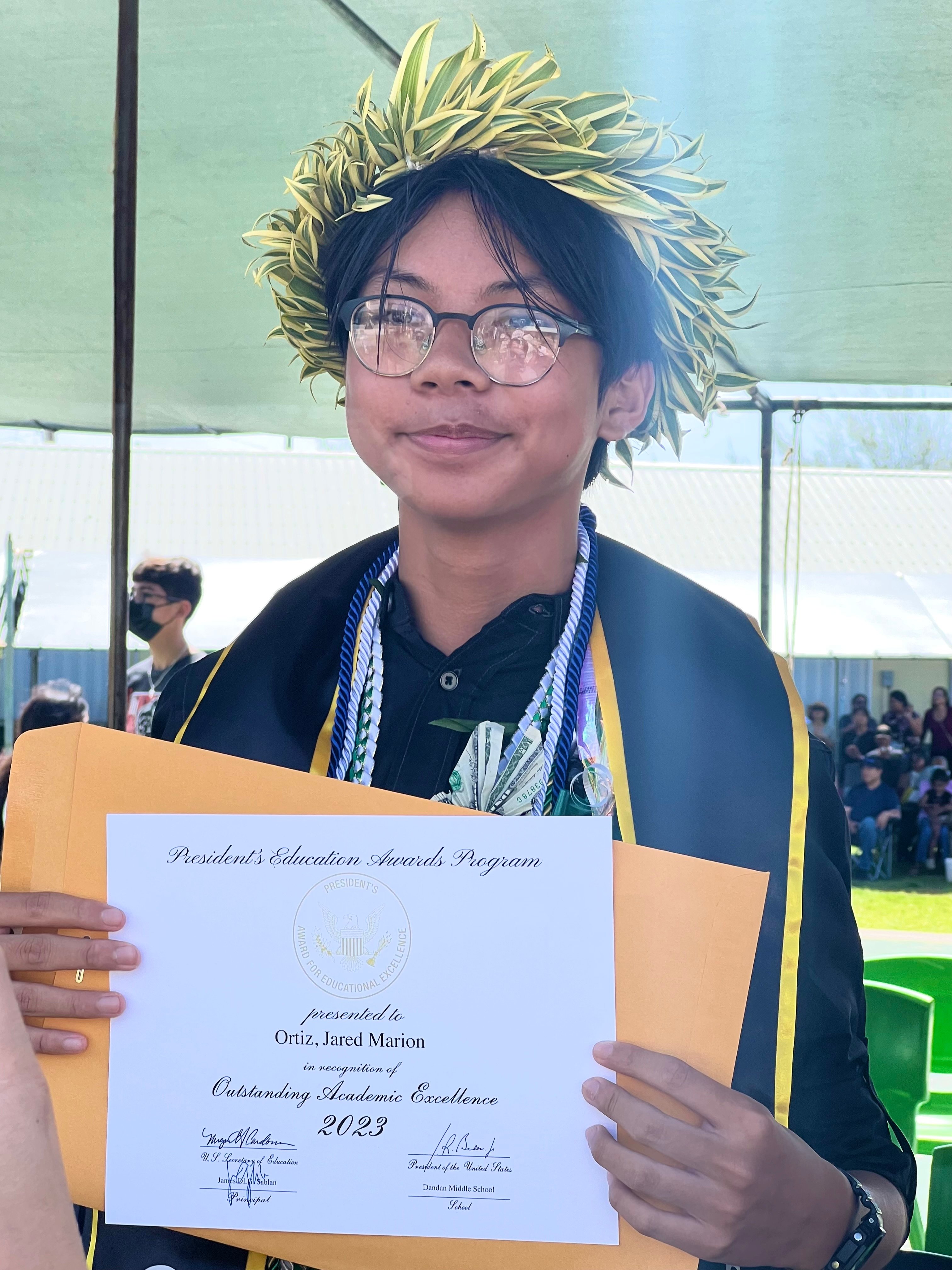 Newly promoted Dandan Middle School student Jared Marion Ortiz smiles after receiving a certificate for Outstanding Academic Excellence.