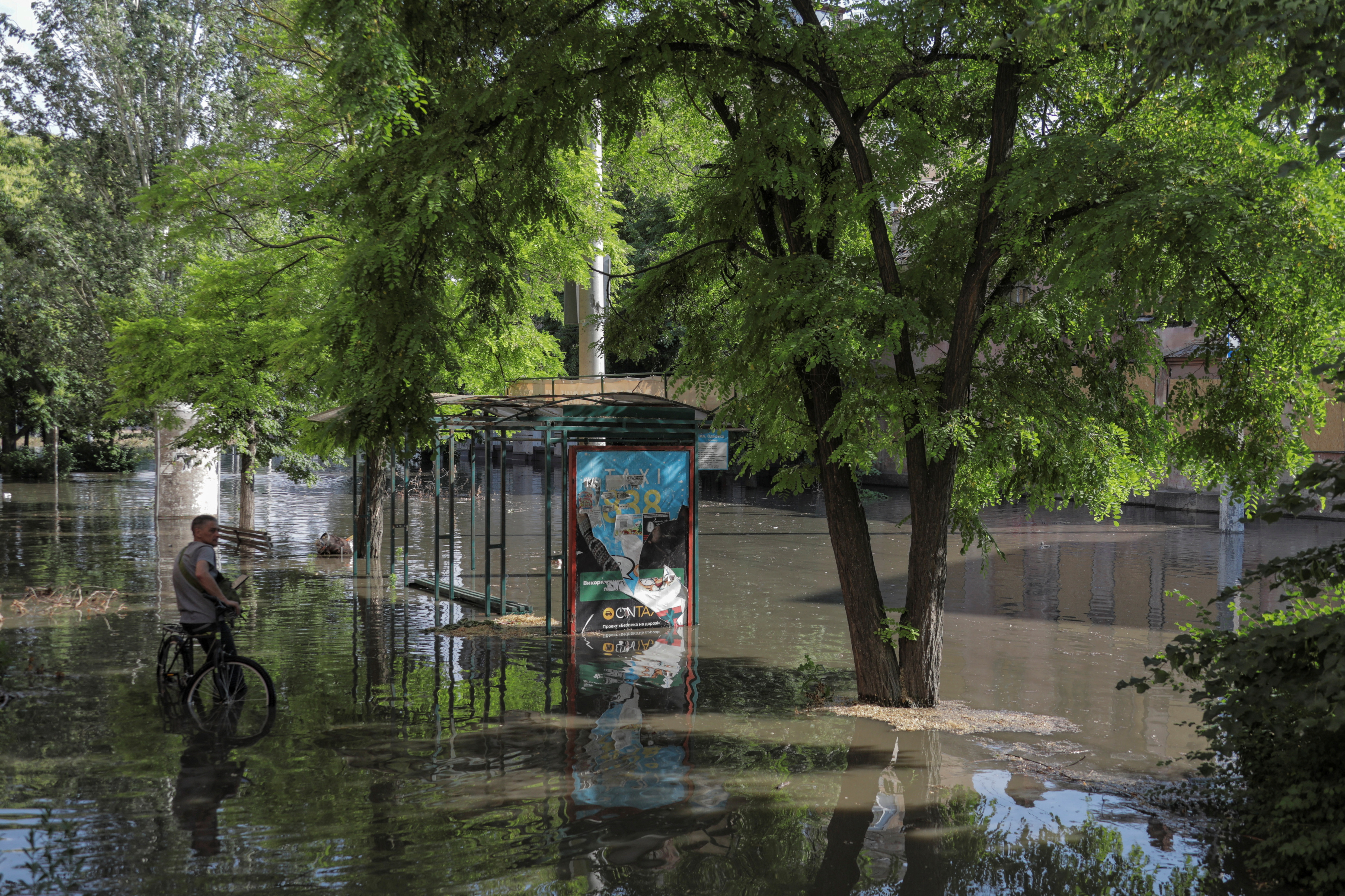 A local resident stands next to a public transport stop on a flooded street after the Nova Kakhovka dam breached, amid Russia's attack on Ukraine, in Kherson, Ukraine June 6, 2023. REUTERS/Stringer
