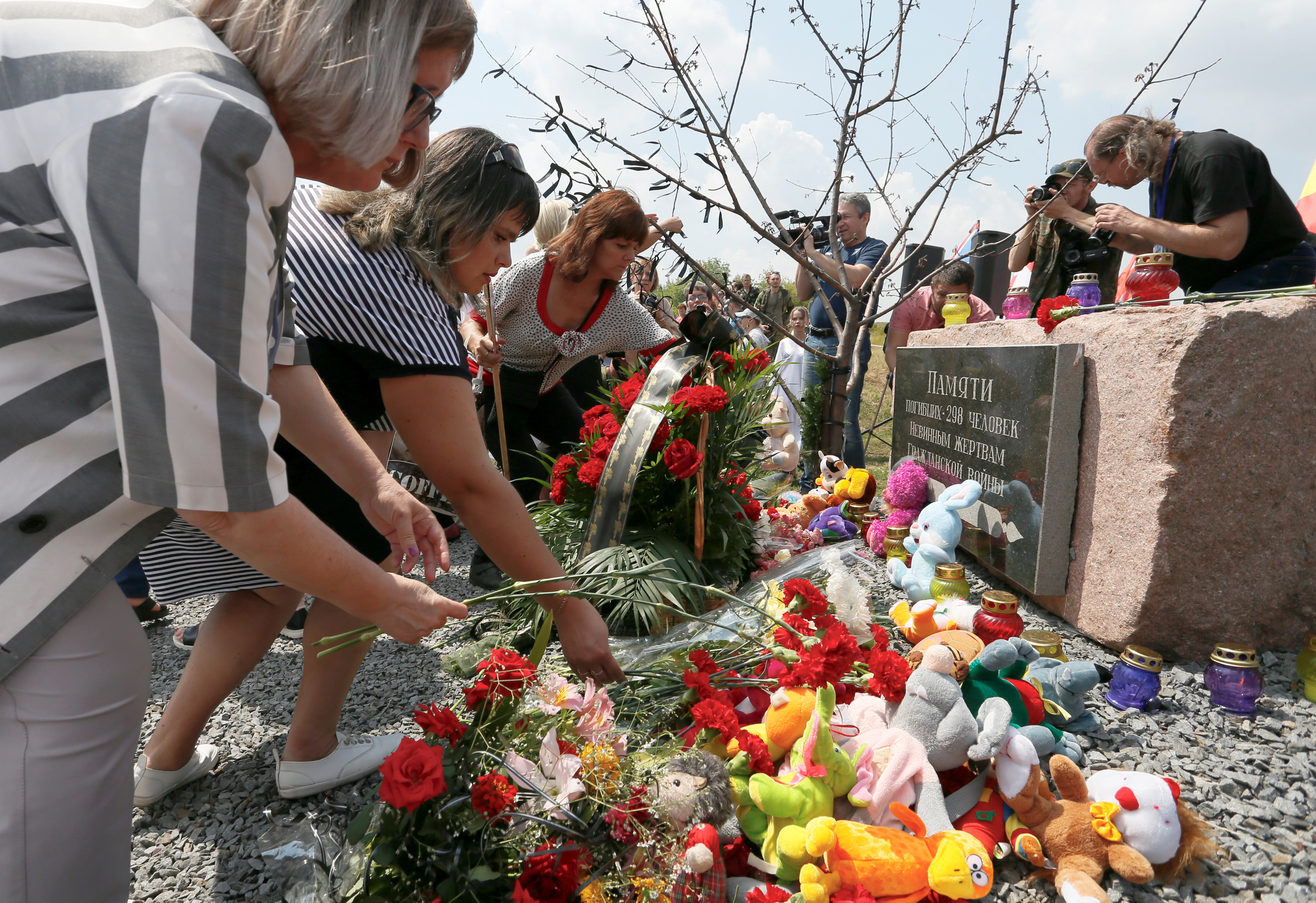 People place flowers and toys at a memorial to victims of the Malaysia Airlines Flight MH17 plane crash during a ceremony marking the fifth anniversary of the accident near the village of Hrabove in Donetsk Region, Ukraine July 17, 2019. REUTERS/Alexander Ermochenko/File Photo