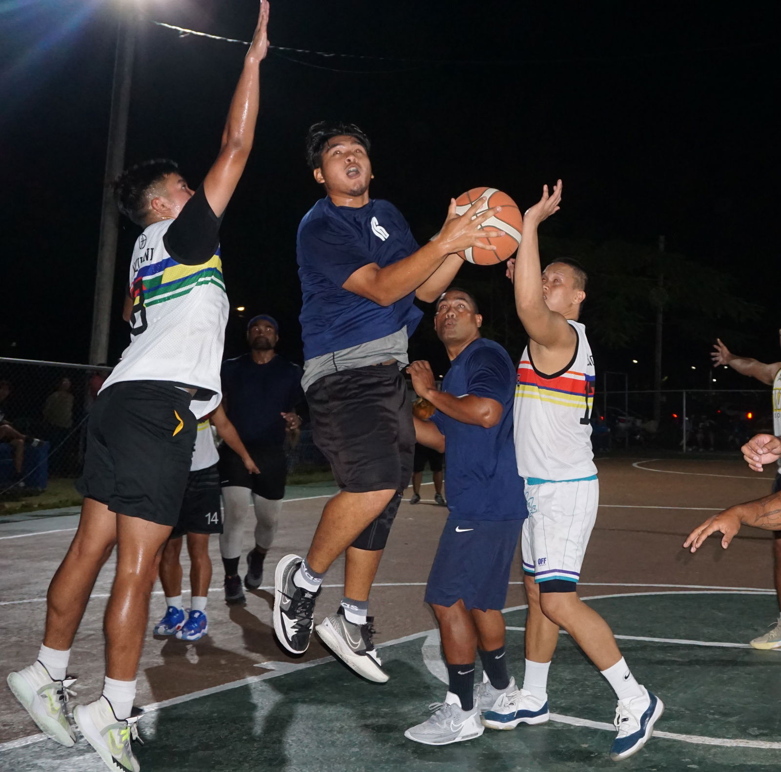 The Martech Ol'Aces' Tyrik Basa protects the ball as he drives between two defenders of The Game during an open division game of the Saipan Centennial Lions Club Invitational Basketball League Wednesday at the Civic Center basketball court.
