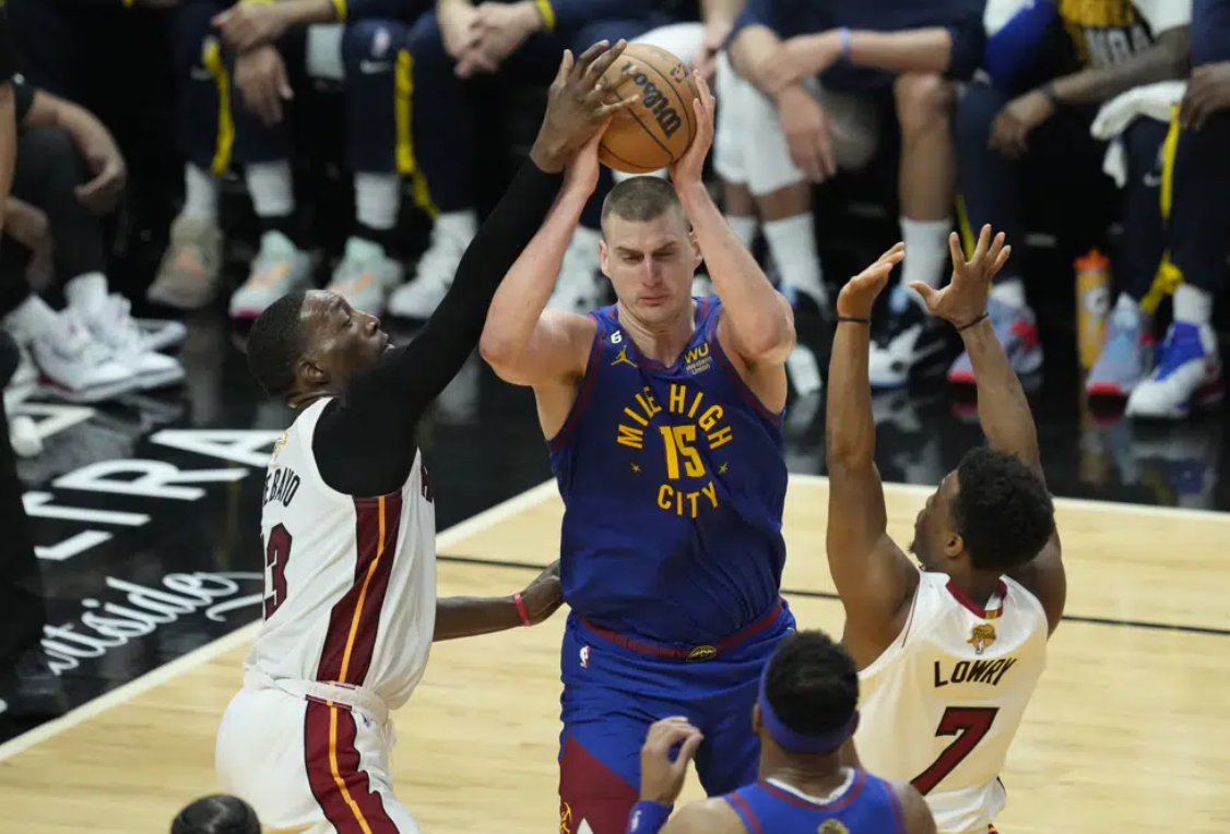 Miami Heat guard Kyle Lowry (7) and center Bam Adebayo (13) defend Denver Nuggets center Nikola Jokic (15) during the first half of Game 3 of the NBA Finals basketball game, Wednesday, June 7, 2023, in Miami.
