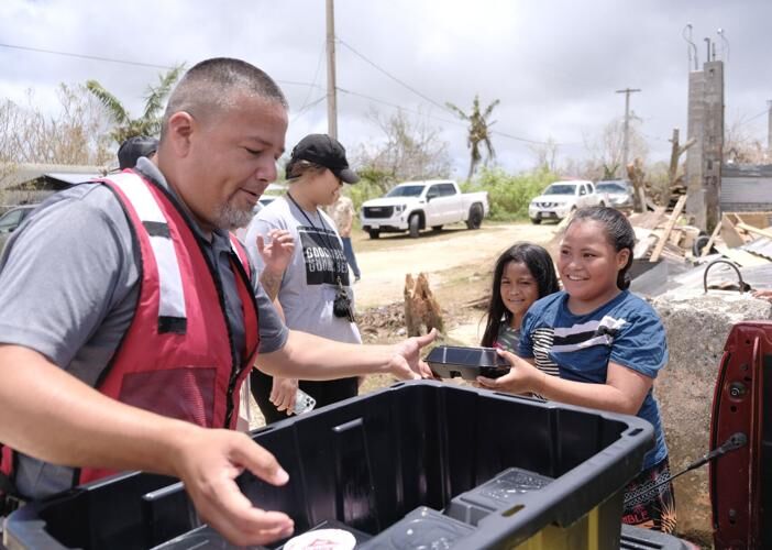Capt. Hector Acosta of the Salvation Army Guam Corps hands a lunch plate from the Hyatt Regency Guam to Kehanymay Williams, 9, as part of a post-Typhoon Mawar outreach in Yigo on Wednesday, June 7, 2023.