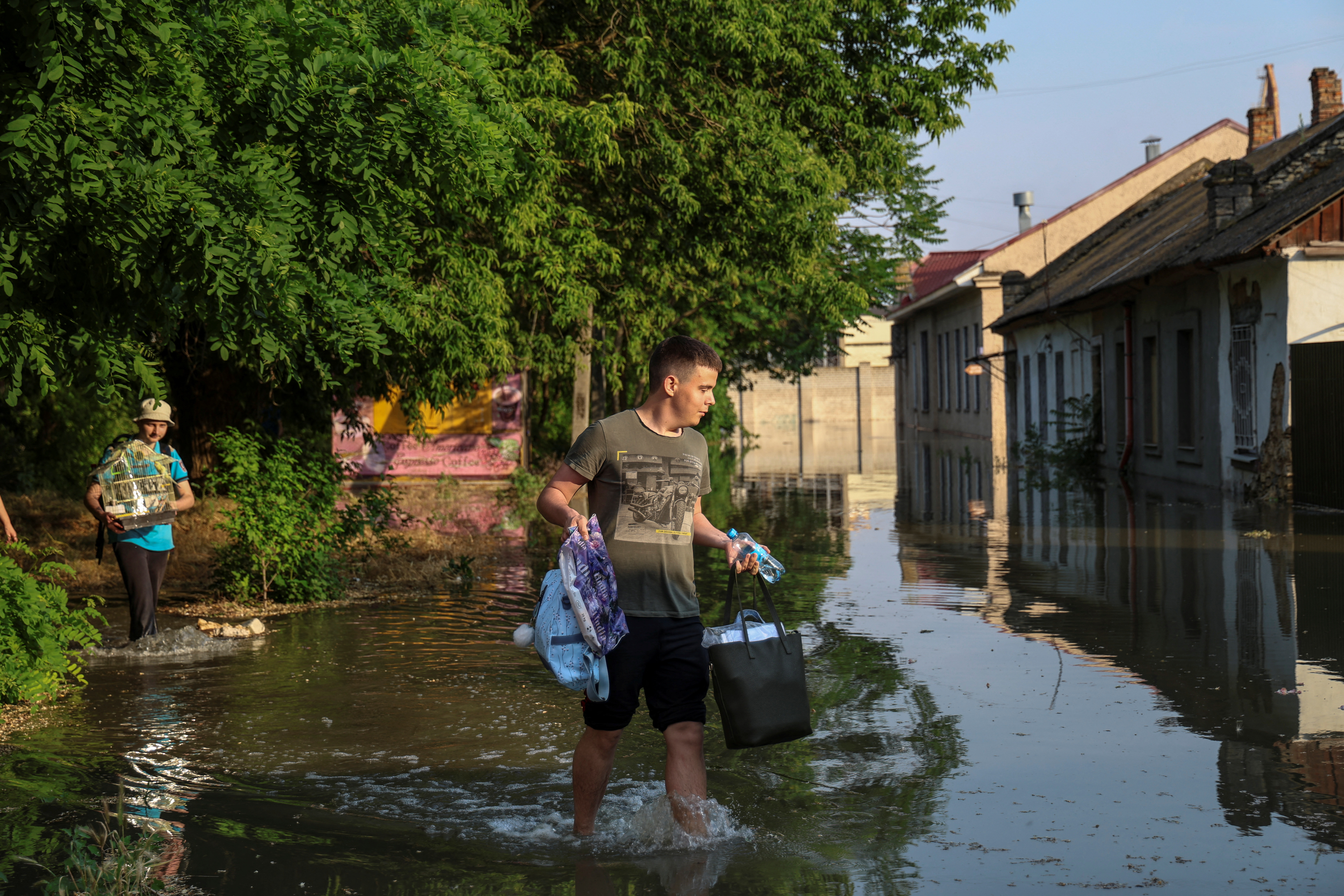 Local residents carry their belongings from a flooded house after the Nova Kakhovka dam breached, amid Russia's attack on Ukraine, in Kherson, Ukraine June 6, 2023. REUTERS/Stringer