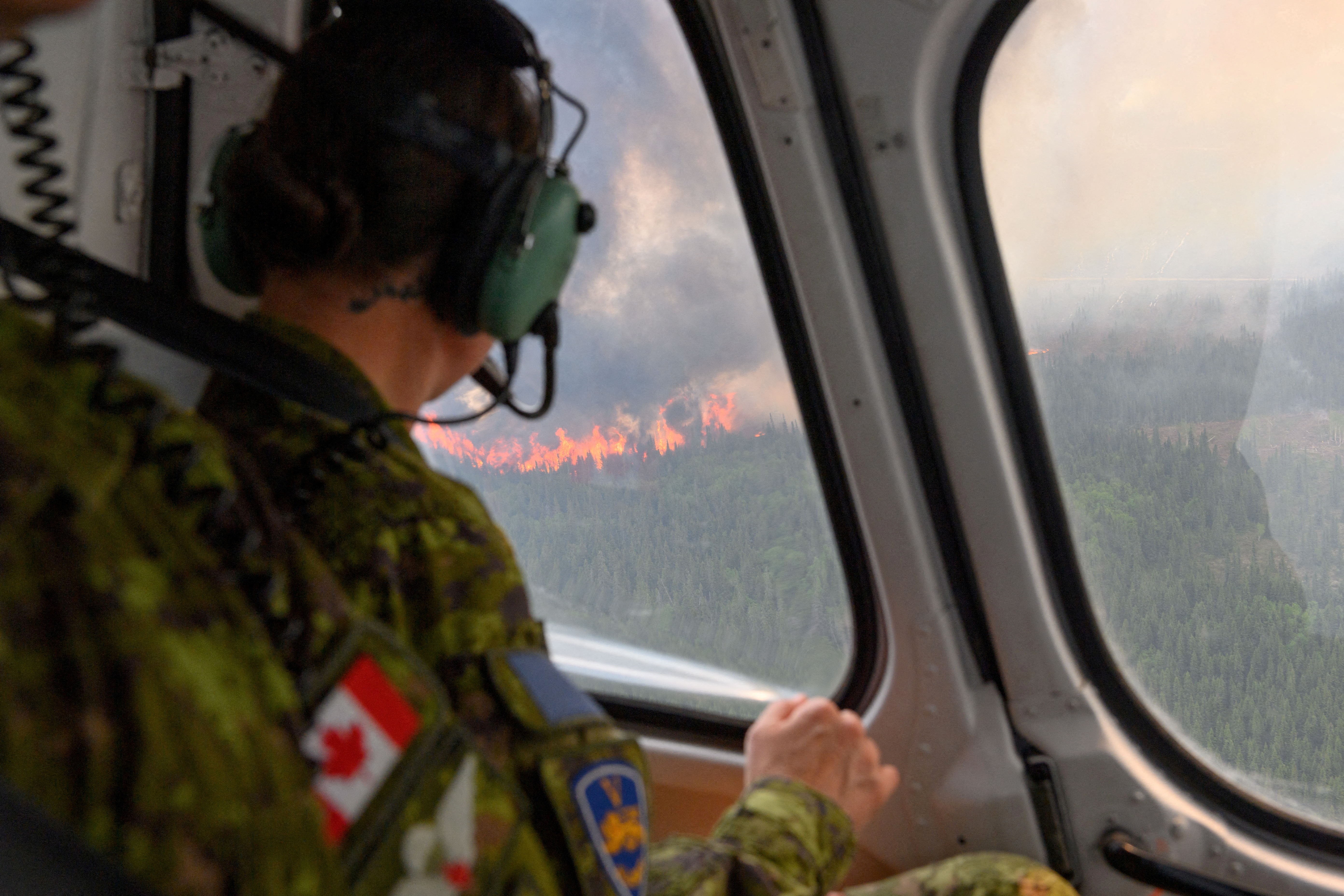 FILE PHOTO: A soldier of the 5th Canadian Mechanized Brigade Group (5 CMBG) views a wildfire from a Canadian Forces helicopter surveying the area near Mistissini, Quebec, Canada June 12, 2023. Cpl Marc-Andre Leclerc/Canadian Forces/Handout via REUTERS/ File Photo