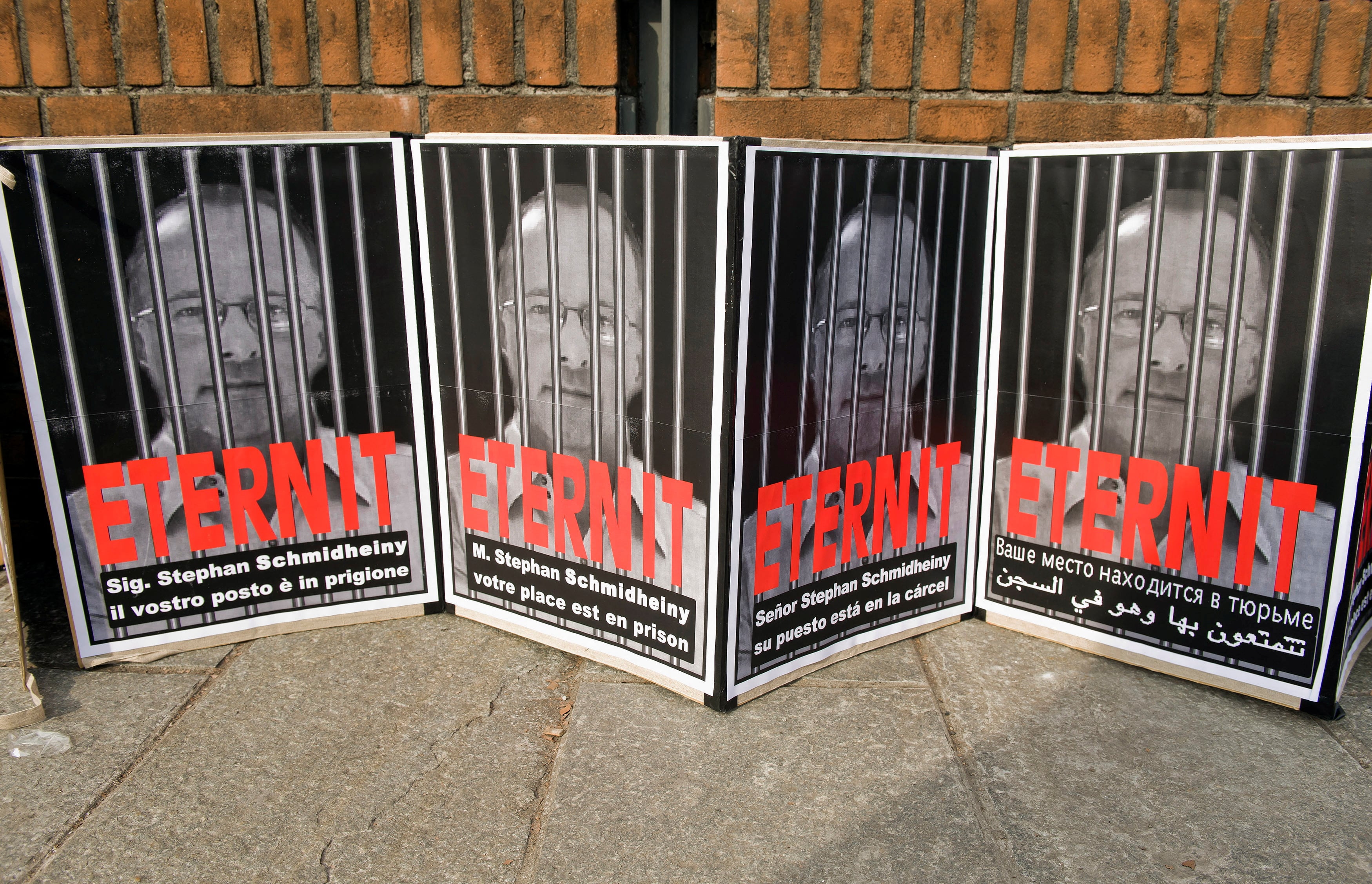 FILE PHOTO: Posters reading "Stephan Schmidheiny your place is in prison" are displayed outside the courthouse during a trial against the Swiss firm Eternit's Italian plant in Turin February 13, 2012. The company closed its Italian operations in 1986. REUTERS/Giorgio Perottino/File Photo