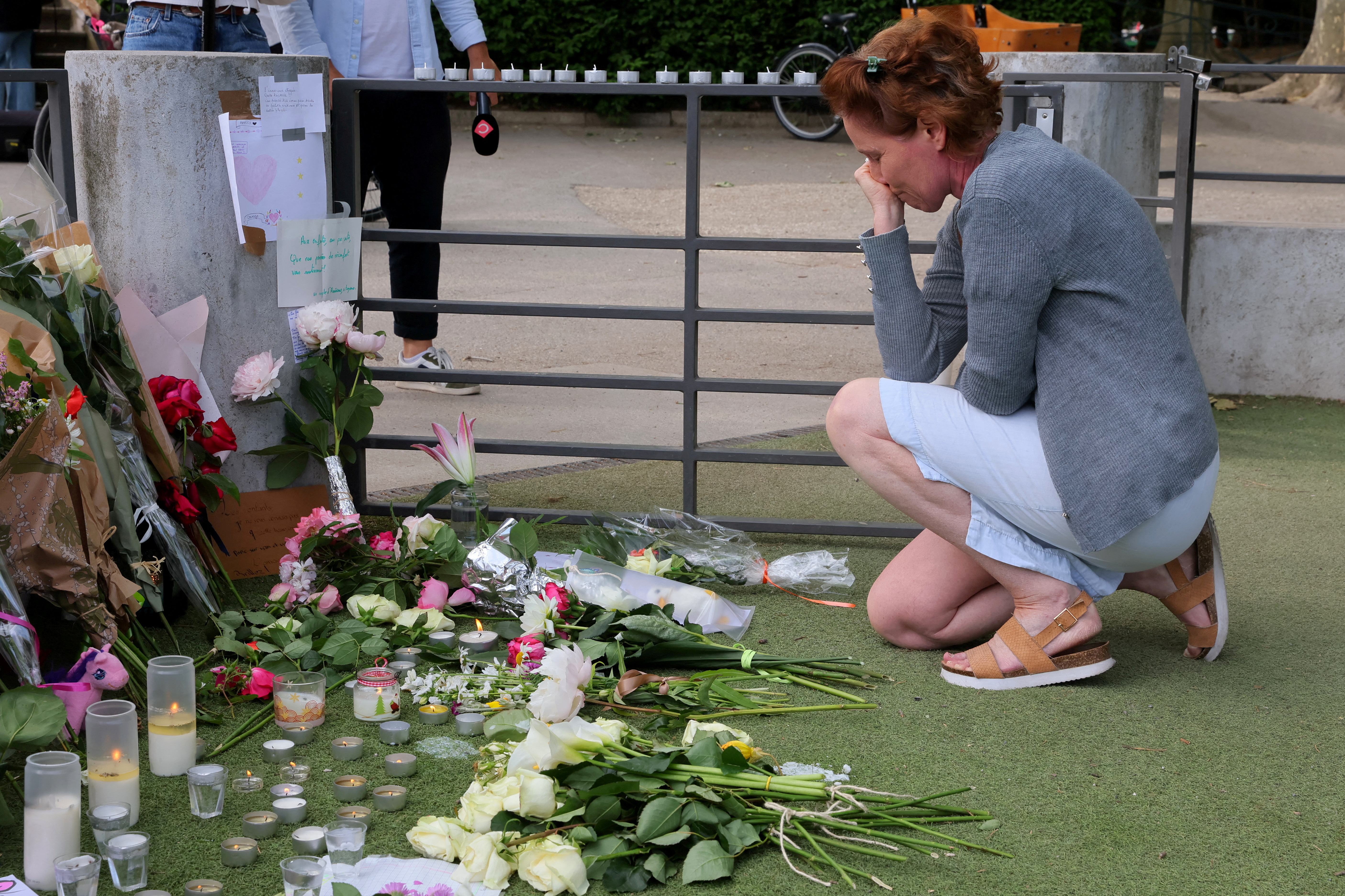 A woman pays respect in front of messages and floral tributes at the children's playground the day after several children and adults were injured in a knife attack at the Le Paquier park near the lake in Annecy, in the French Alps, France, June 9, 2023. REUTERS/Denis Balibouse