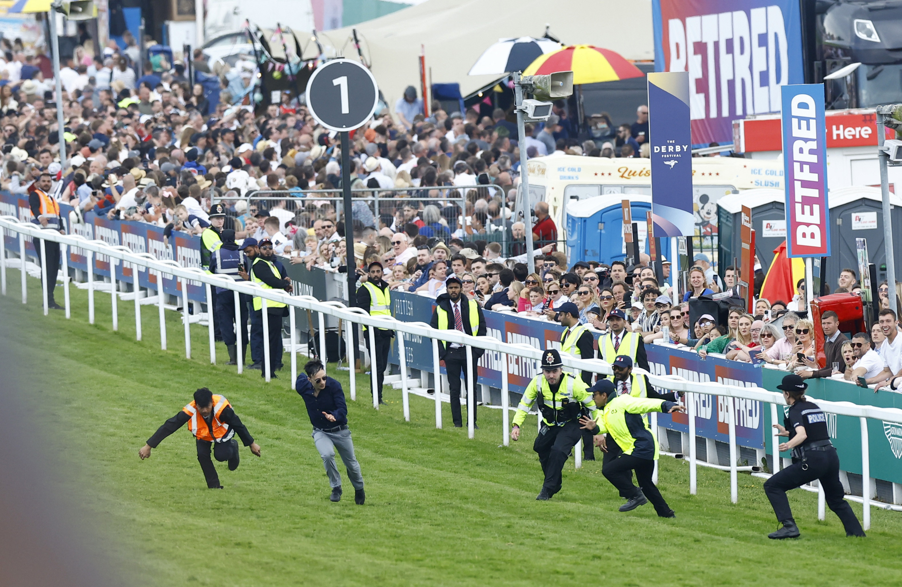 Horse Racing - Epsom Derby Festival - Epsom Downs Racecourse, Epsom, Britain - June 3, 2023 Animal Rising activists walk onto the race track as police officers chase them during the 13:30 Betfred Derby Action Images via Reuters/Peter Cziborra