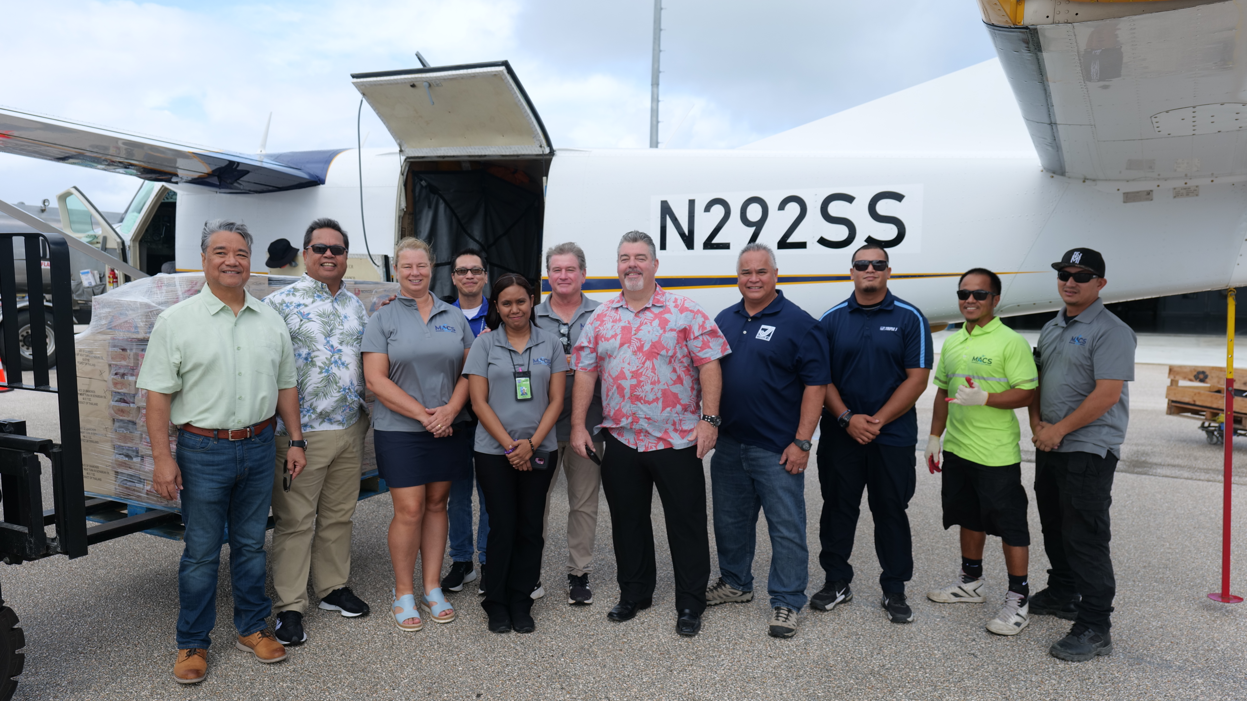 From left, representatives from Triple J Saipan and Micronesian Air Cargo Services stand beside the pallet of food items at Saipan International Airport before the food items are shipped to Rota in support of Super Typhoon Mawar relief efforts on Friday, June 2.