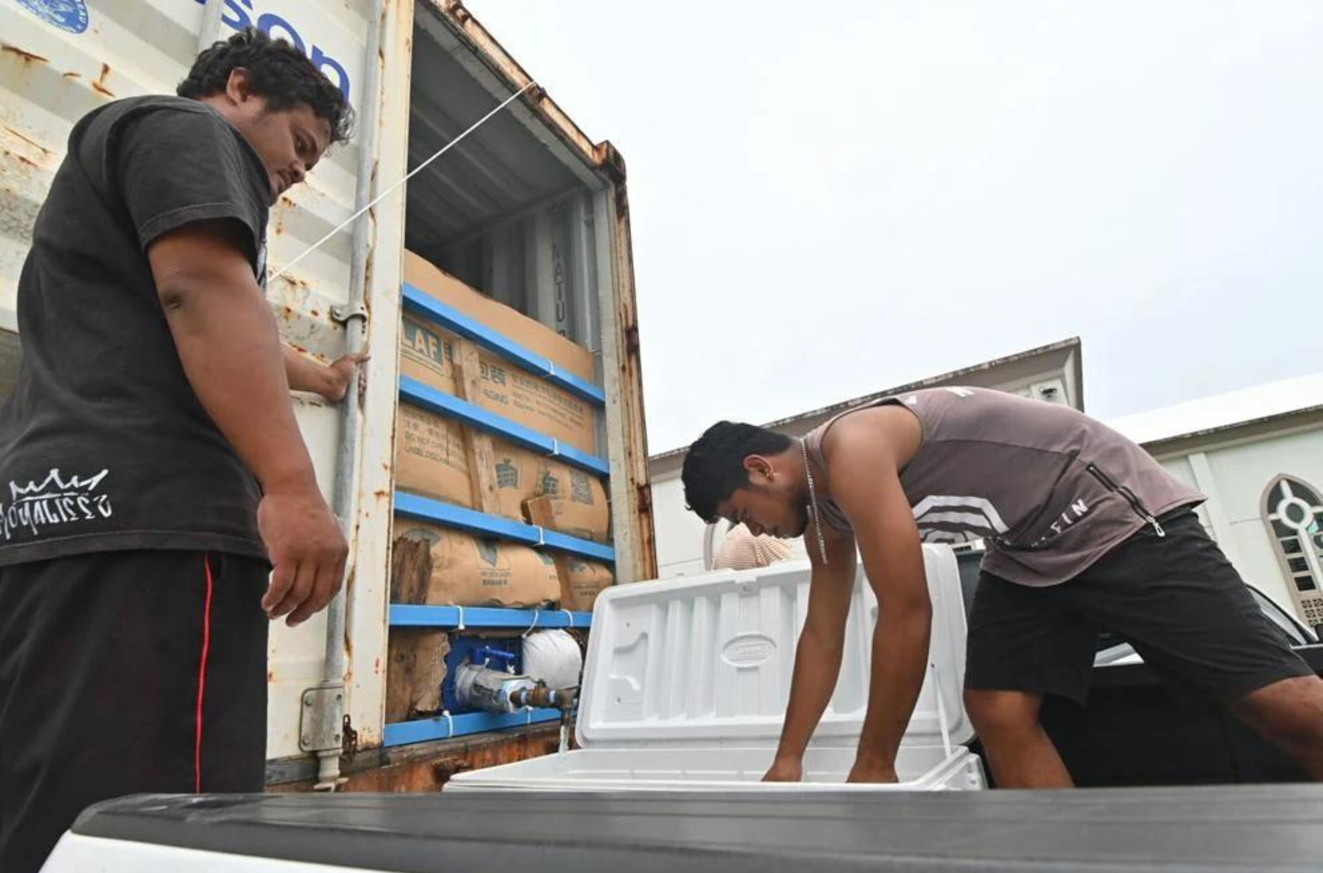 Jester "JB" Benjamin and Joel Hyle, from Mangilao, fill coolers from a water tanker positioned at the village's Santa Teresita Catholic Church on Sunday, June 4, 2023. 