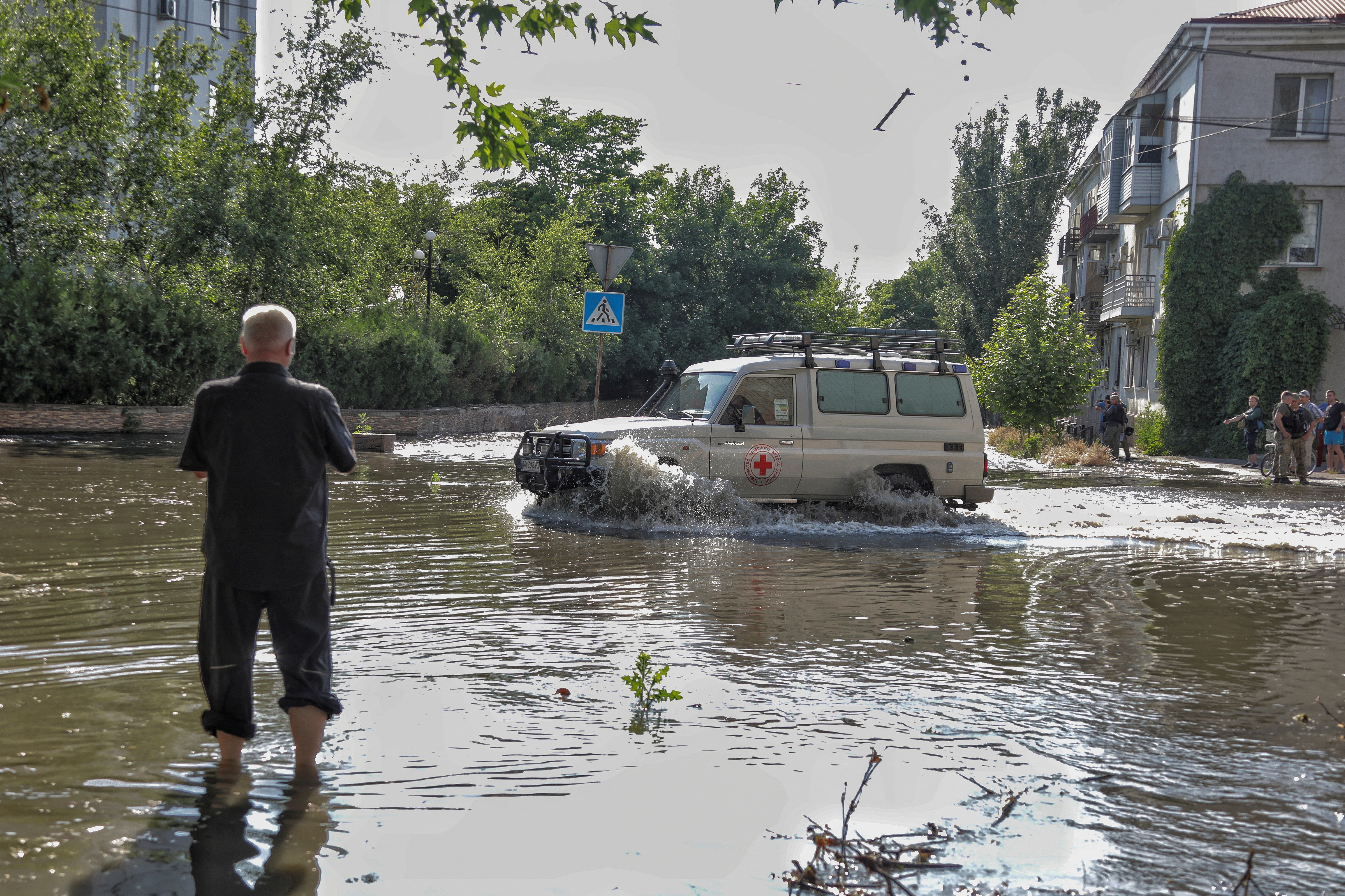 Red Cross volunteers drive a car on a flooded street after the Nova Kakhovka dam breached, amid Russia's attack on Ukraine, in Kherson, Ukraine June 6, 2023. REUTERS/Stringer