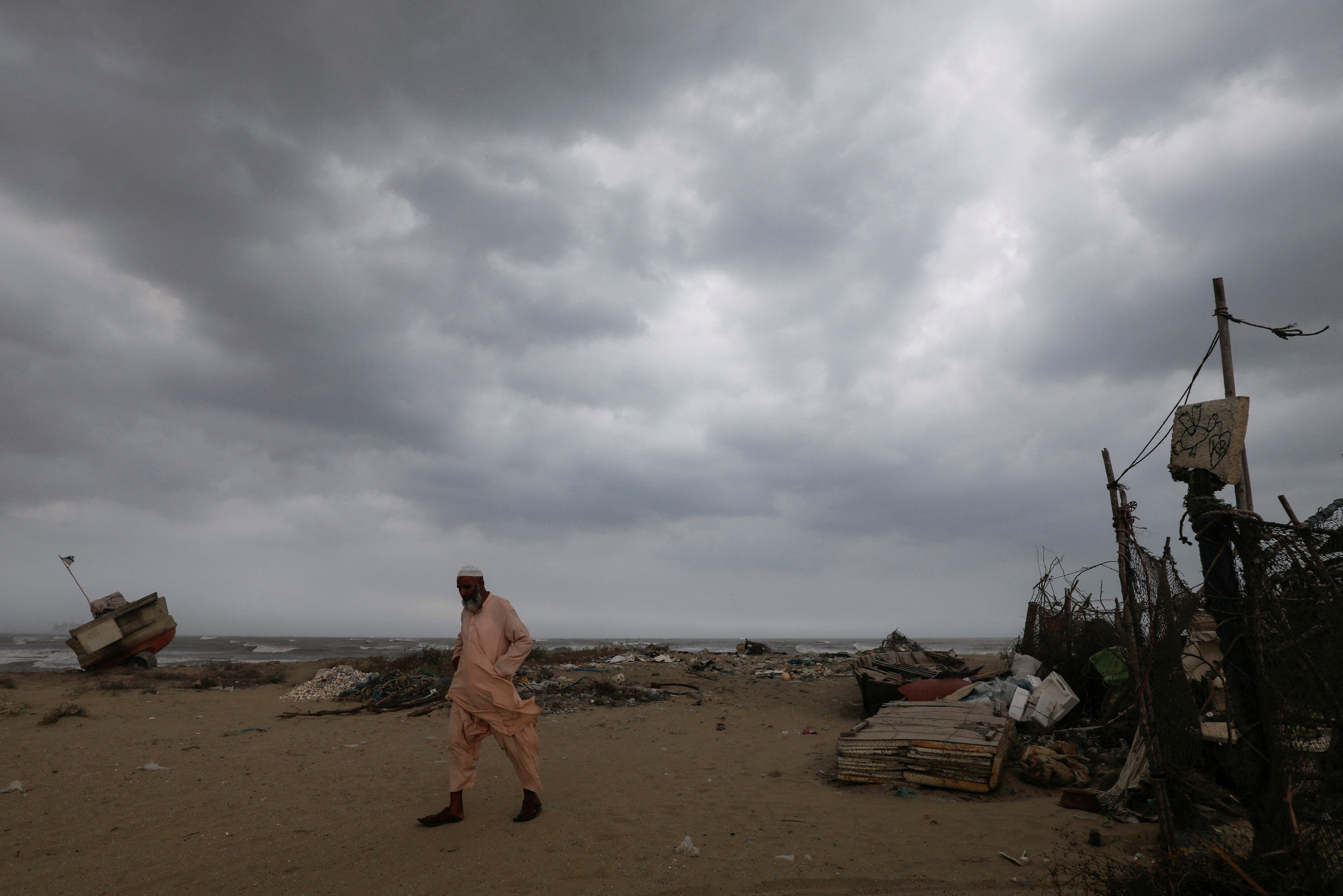 Amjad Khan, 48, a boat maker, walks with the rain clouds in the background, before the arrival of cyclonic storm, Biparjoy, over the Arabian Sea, in Karachi, Pakistan June 15, 2023. REUTERS/Akhtar Soomro