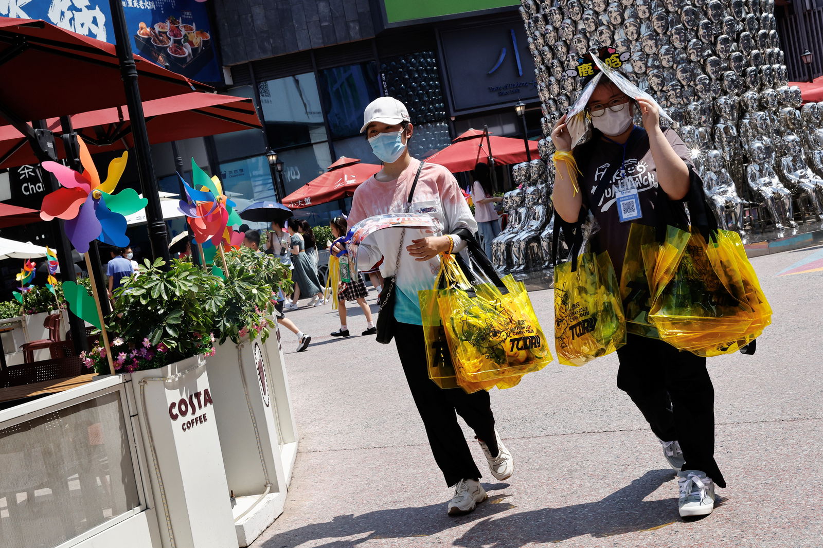 People shield themselves from the sun, as they walk amid a red alert for heatwave in Beijing, China June 23, 2023. REUTERS/Tingshu Wang