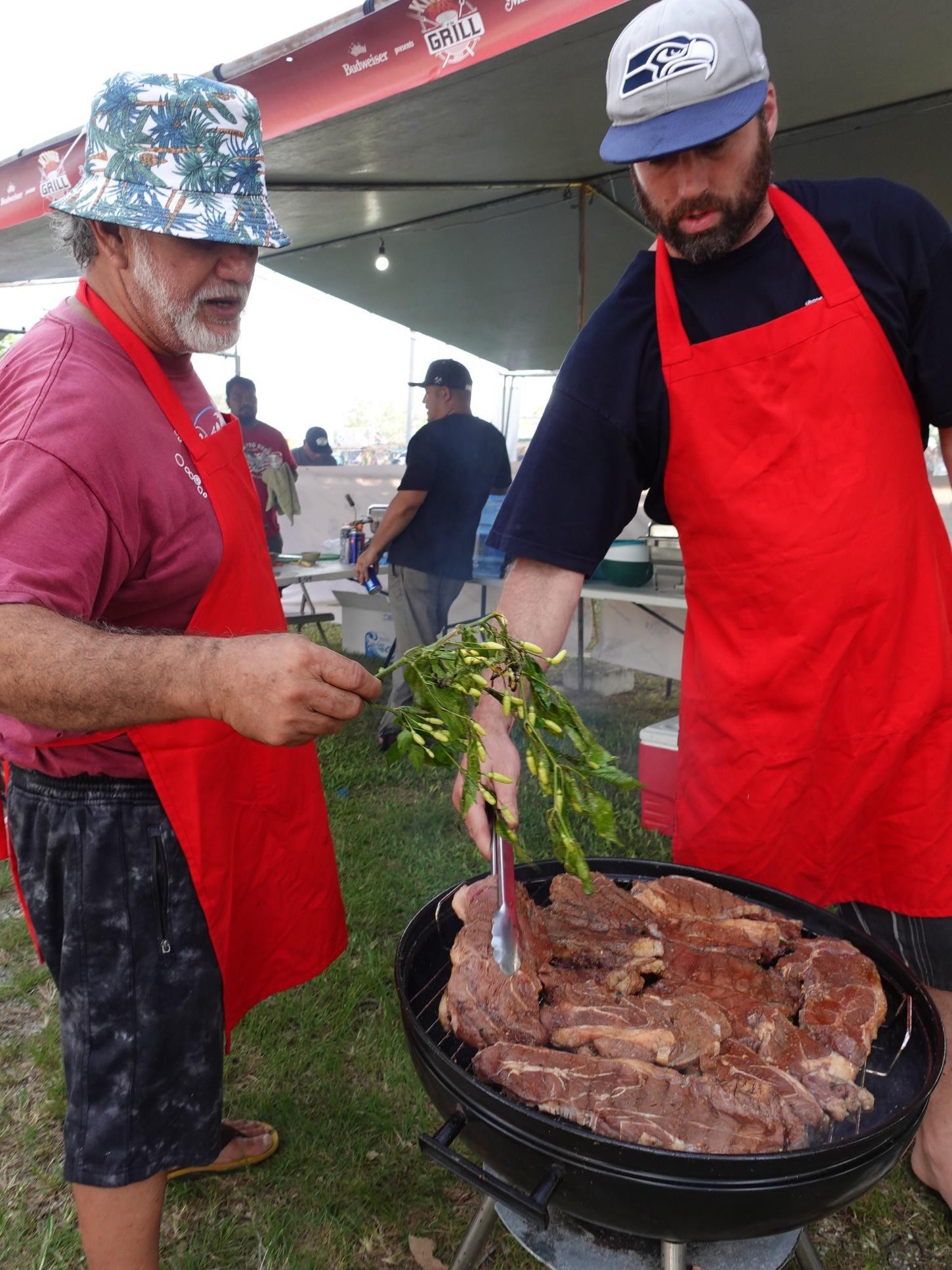 Alexander Standish, right, and his father-in-law Donald Mendiola use the famous “donne sali” (hot pepper) in their entry to Budweiser’s King of the Grill at the 24th Annual Taste of the Marianas International Food Festival & Beer Garden on June 17, 2023, at Garapan Fishing Base, Saipan. The duo won 2nd place for best steak and 3rd place for best ribs.