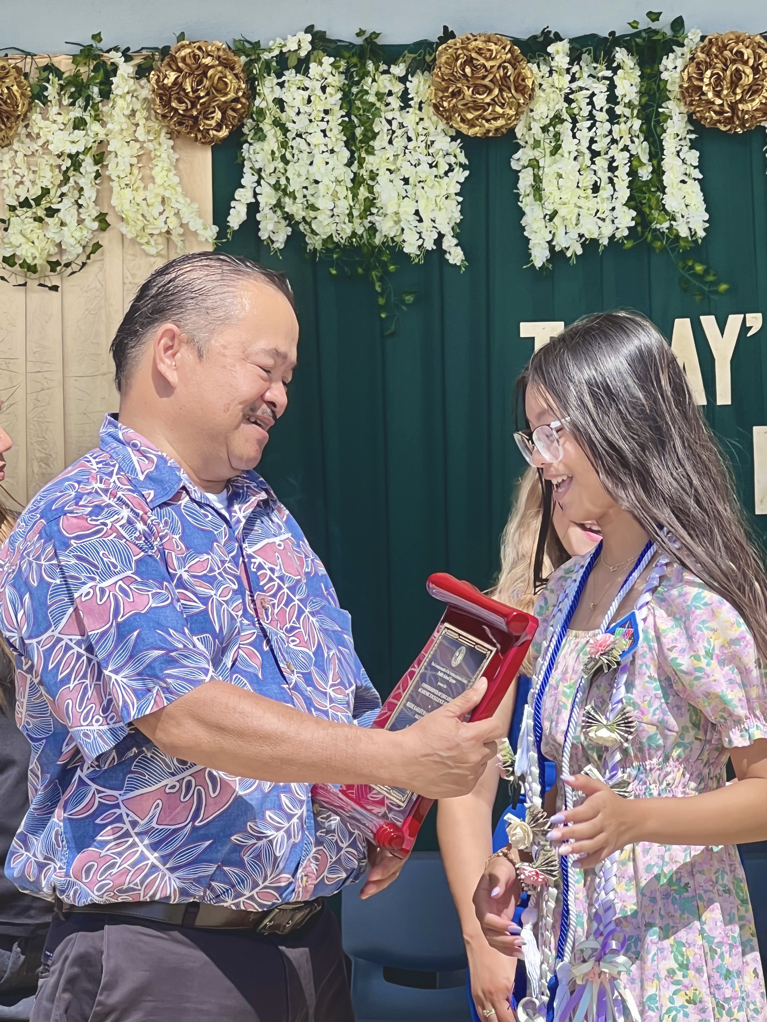 Commissioner of Education Dr. Alfred B. Ada presents the Commissioner of Education Academic Excellence Award to the class salutatorian, Reese Kaeley Tolentino.