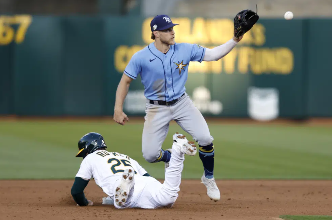 Oakland Athletics' Brent Rooker (25) dives into second on a pickoff-attempt by Tampa Bay Rays' Taylor Walls, right, during the fifth inning of a baseball game in Oakland, Calif., Monday, June 12, 2023.