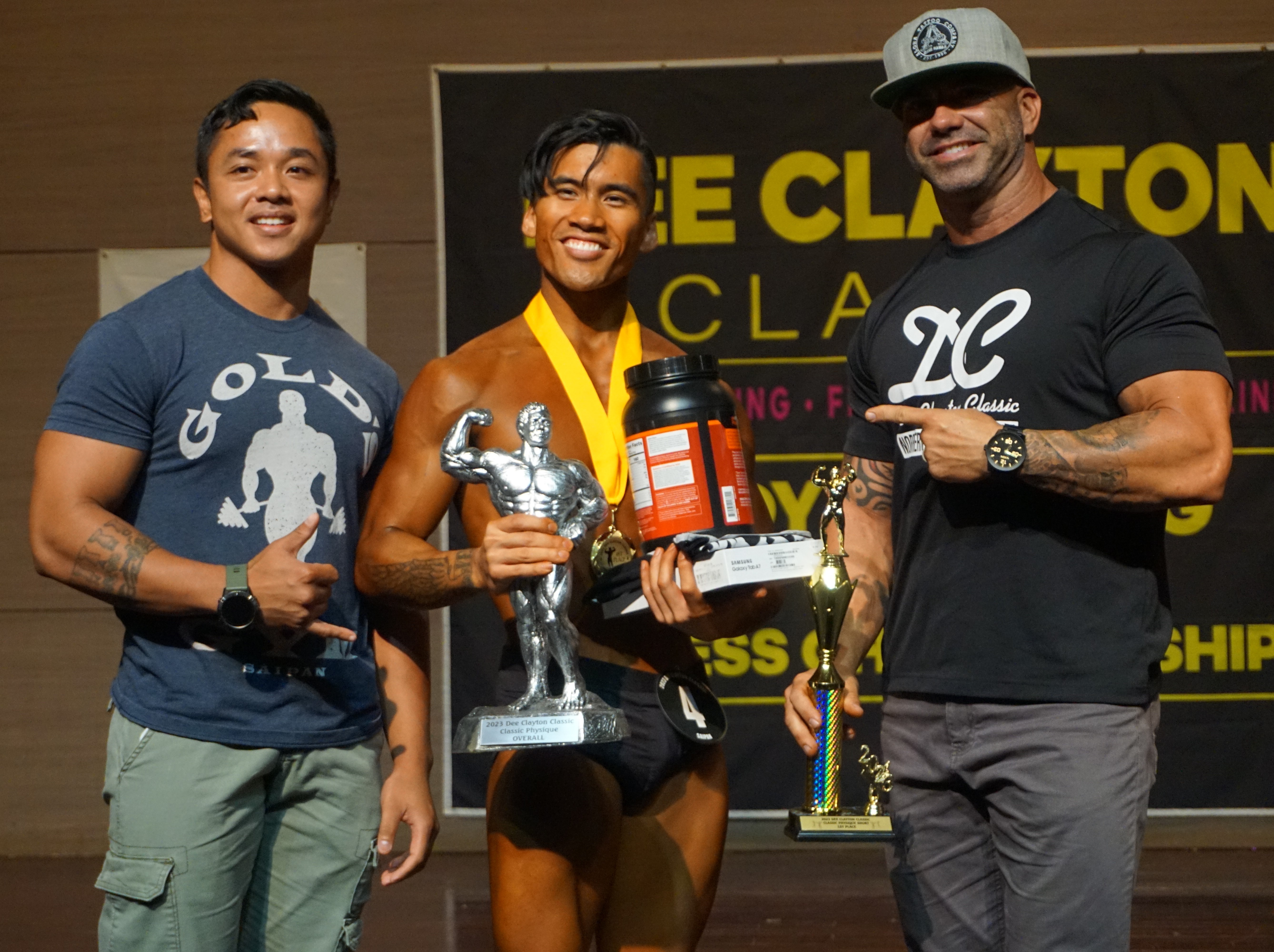 Lorenzo Sanchez holds the classic physique overall trophy as he poses for a photo with Gold’s Gym certified personal trainer Gerald Galang, left, and Latte Built owner Derek Cutting, right, at the conclusion of the 2023 Dee Clayton Classic & Northern Marianas Bodybuilding Federation competition at Saipan World Resort's Taga Hall.