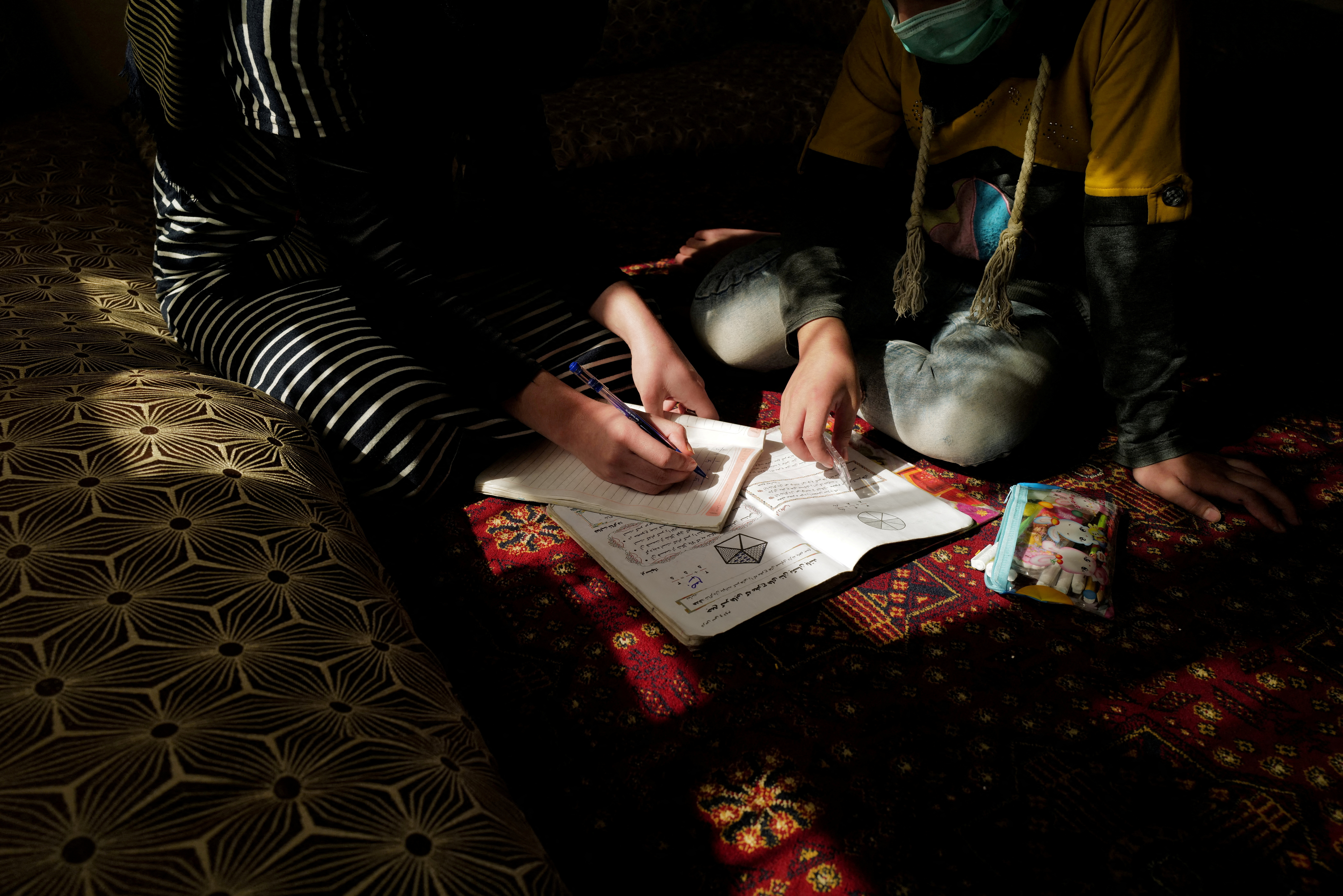 FILE PHOTO: Sahar, 17, an 11th grade secondary school student, helps her sister, Hadia, 10, a 4th grade primary school student, with her homework after school at their home in Kabul, Afghanistan, October 26, 2021. REUTERS/Zohra Bensemra/File Photo