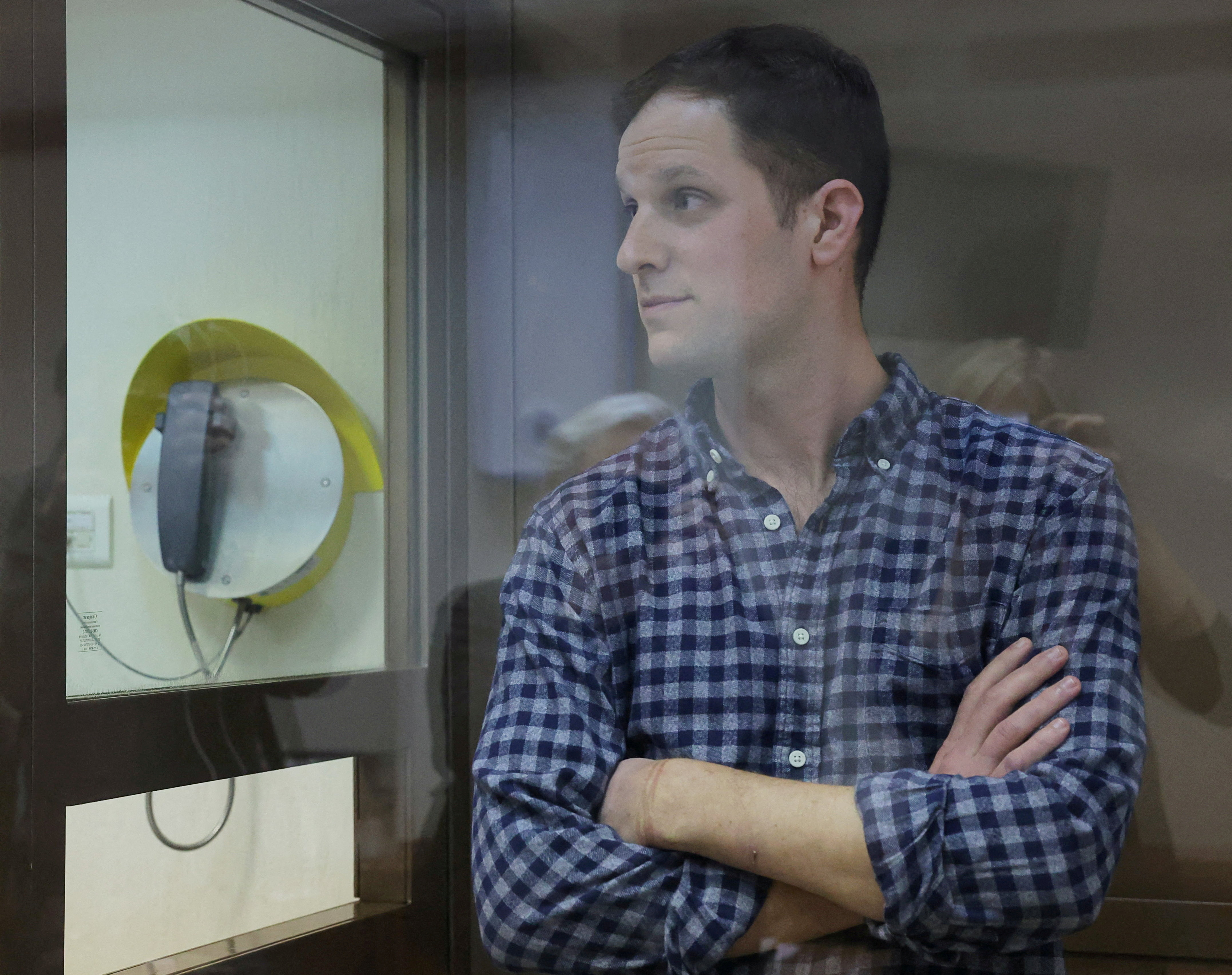 FILE PHOTO: Wall Street Journal reporter Evan Gershkovich, who was detained in March while on a reporting trip and charged with espionage, stands behind a glass wall of an enclosure for defendants before a court hearing to consider an appeal against his detention, in Moscow, Russia April 18, 2023. REUTERS/Evgenia Novozhenina/File Photo