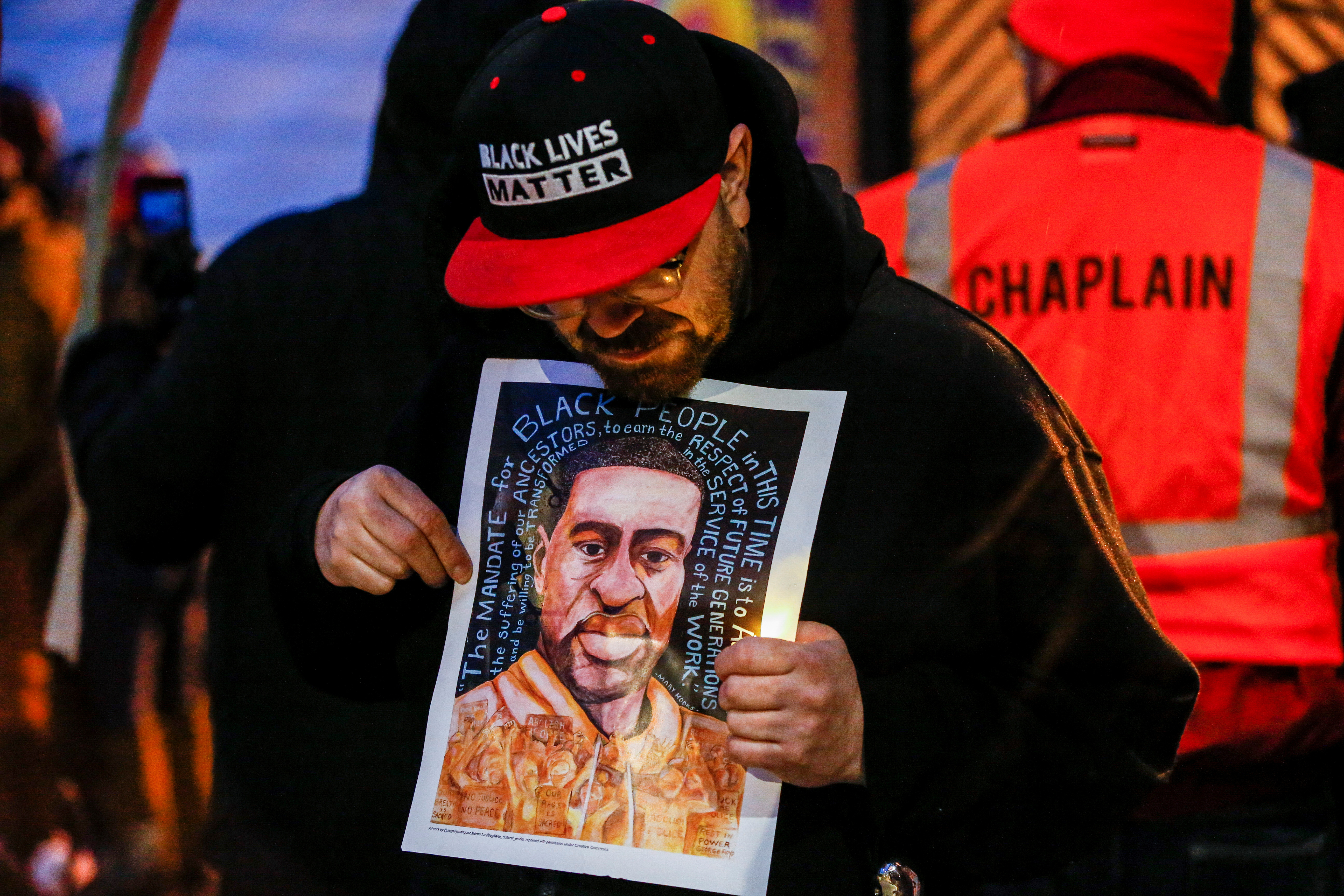 FILE PHOTO: A man holds an image of George Floyd at a vigil on the second anniversary of the death of Floyd, a black man who was killed in 2020 by white police officer Derek Chauvin by kneeling on his neck, in Minneapolis, Minnesota, U.S. May 25, 2022. REUTERS/Eric Miller/File Photo