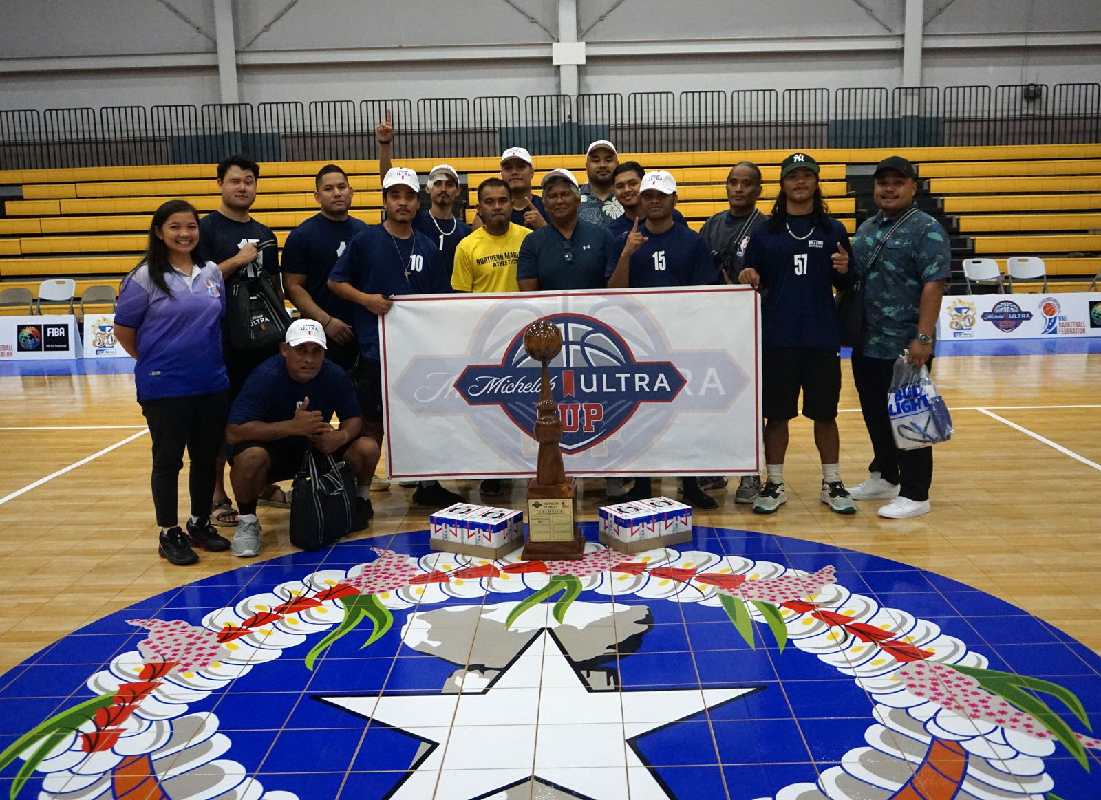 The Ol'Aces and sponsor Alan Lebria of Martech pose with the Michelob Ultra Cup championship trophy and tournament director Marlene Lumabi during the awards ceremony Tuesday at the Ada gym.
