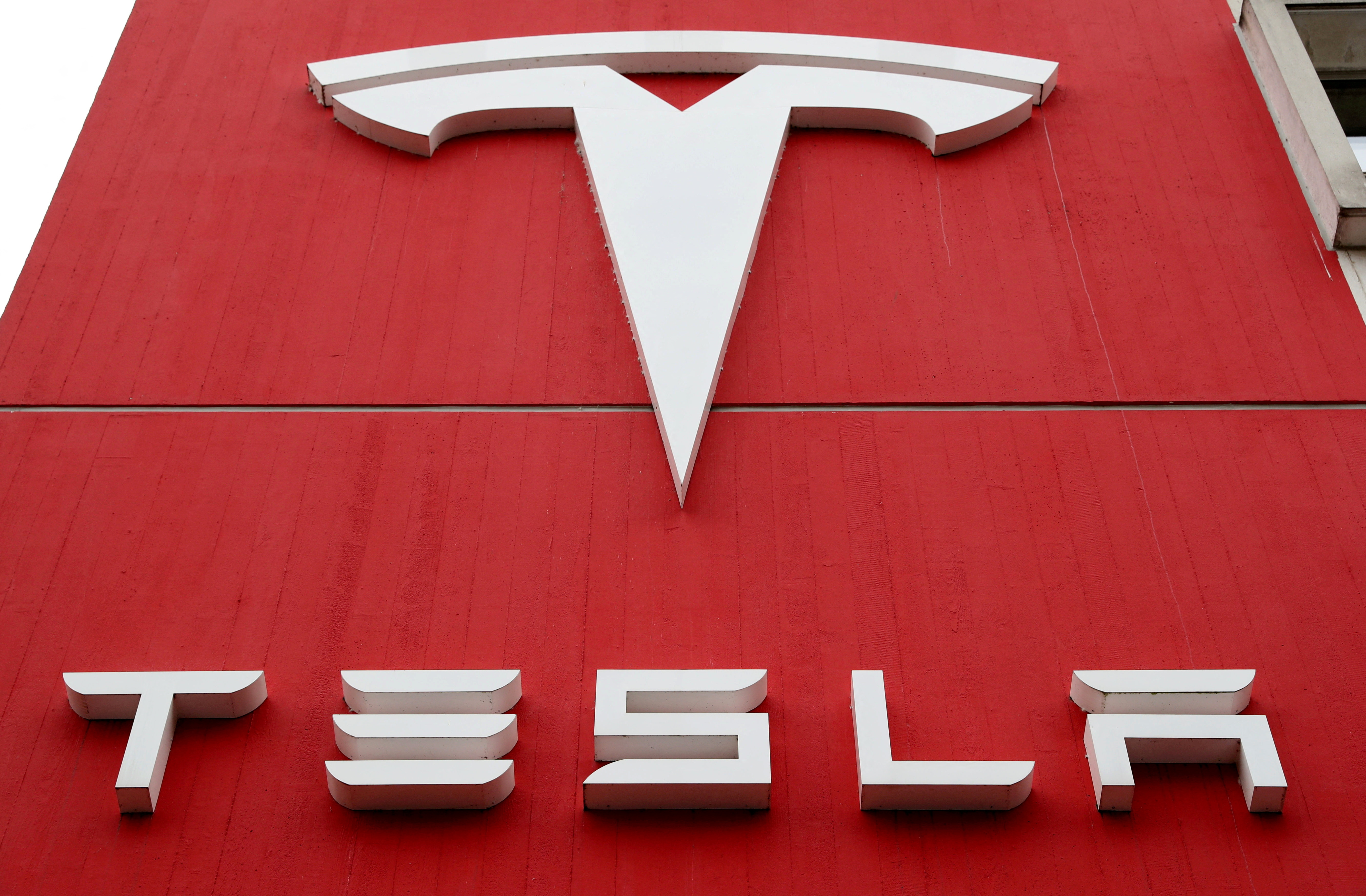 FILE PHOTO: he logo of car manufacturer Tesla is seen at a branch office in Bern, Switzerland October 28, 2020. REUTERS/Arnd Wiegmann/File Photo