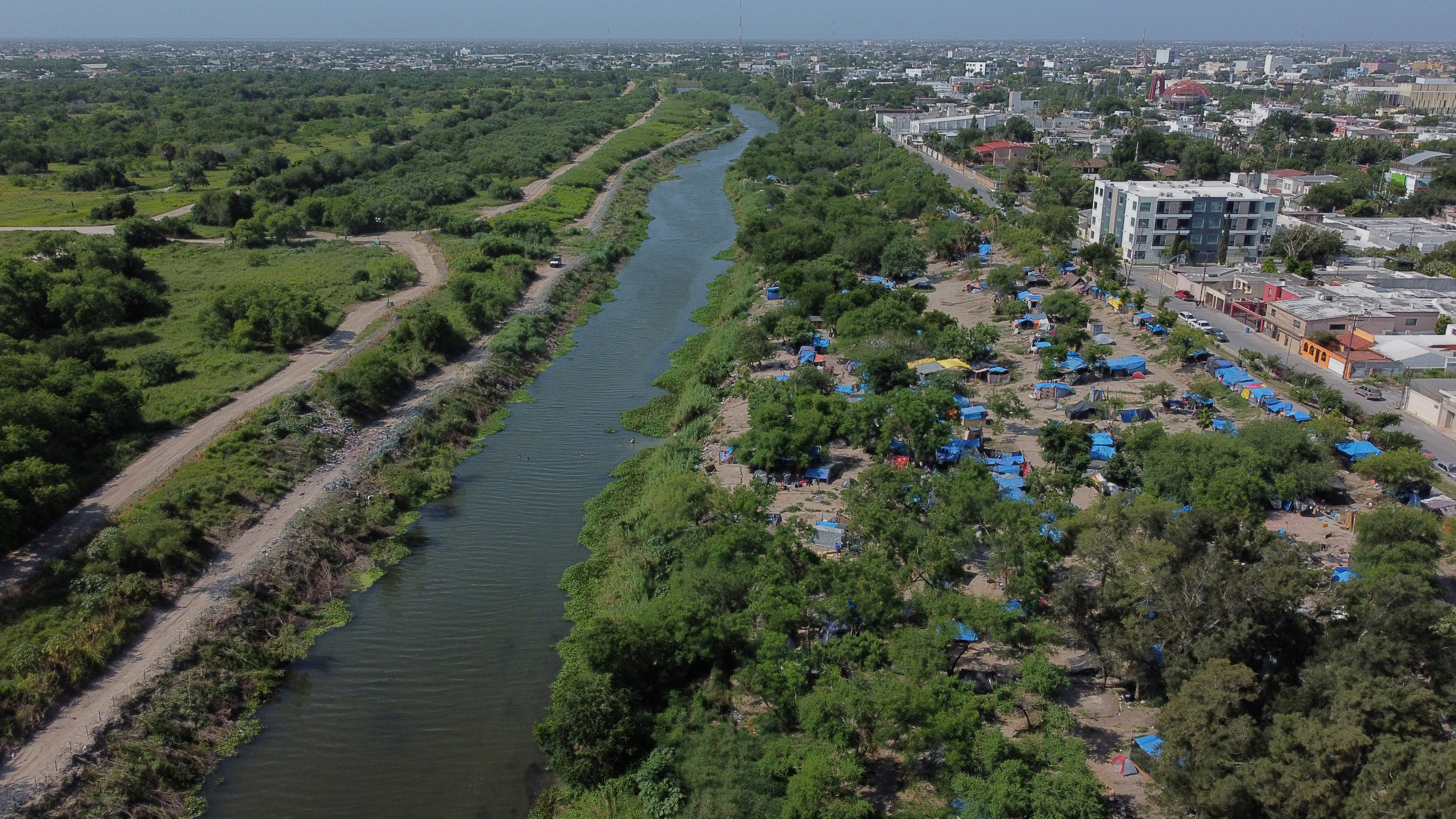 A makeshift camp, where asylum seekers wait as they attempt to cross into the U.S. by an appointment through the Customs and Border Protection app, called CBP One, lines the Rio Grande river border between Brownsville, Texas and Matamoros, in Matamoros, Mexico June 20, 2023. President Joe Biden promised to replace the hardline policies of former President Donald Trump, including the COVID-era public health order Title 42, with a more humane immigration system. The new Biden regulation allows migrants once again to ask for asylum at the border, but wait in Mexico for a slot on the app or risk a sped-up deportation process that could be conducted while they are held in detention. But in the first month of the new policy, Reuters found tens of thousands of people are waiting in dangerous Mexican border towns to snag a spot on the app, according to U.S. and Mexican officials, amid warnings from humanitarian groups of deteriorating sanitary conditions at migrant camps. REUTERS/Daniel Becerril