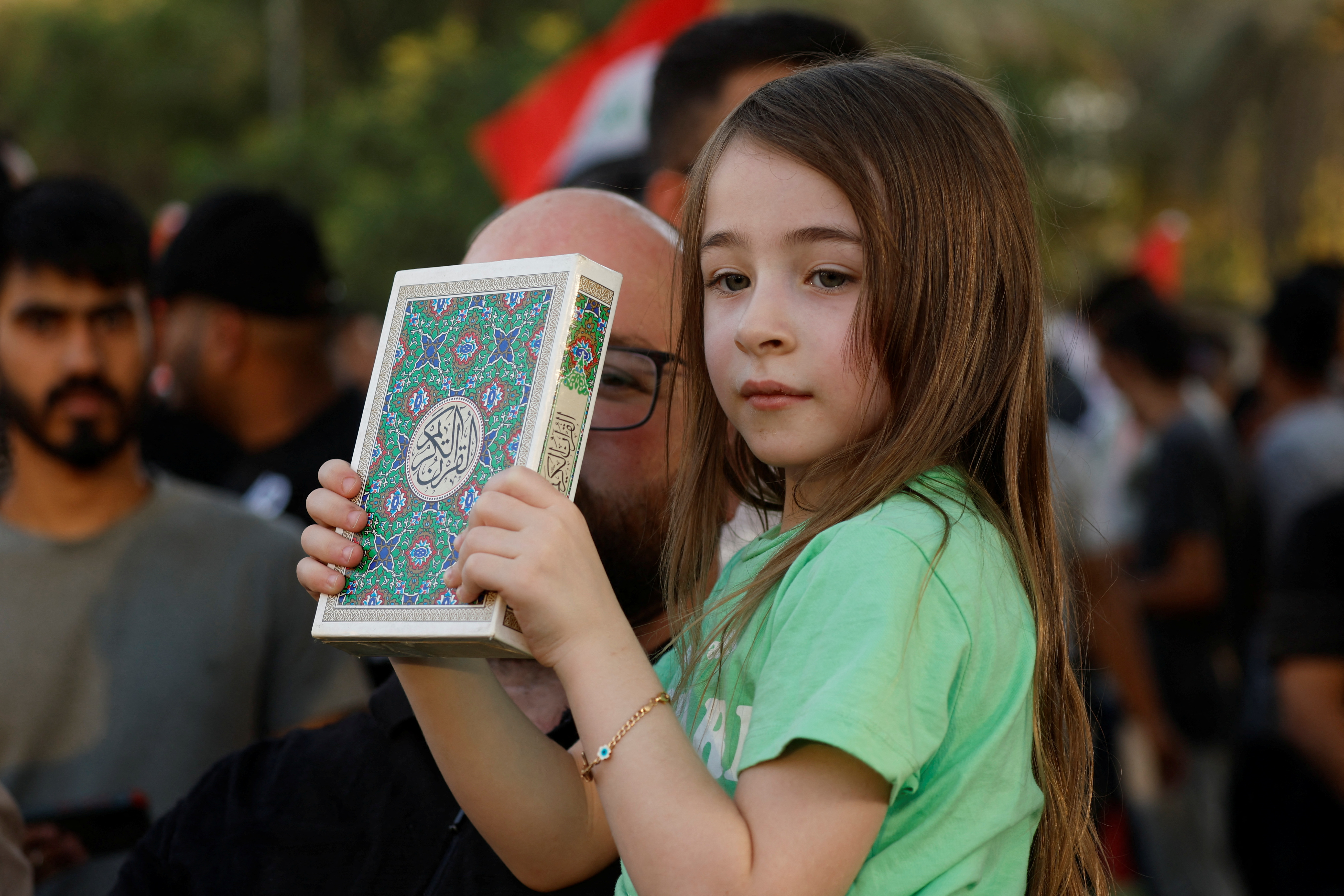 A child holds the Koran during a protest near the Green Zone against the burning of a copy of the Koran and the Iraqi flag in the Swedish capital Stockholm, in Baghdad, Iraq July 22, 2023. REUTERS/Khalid Al-Mousily