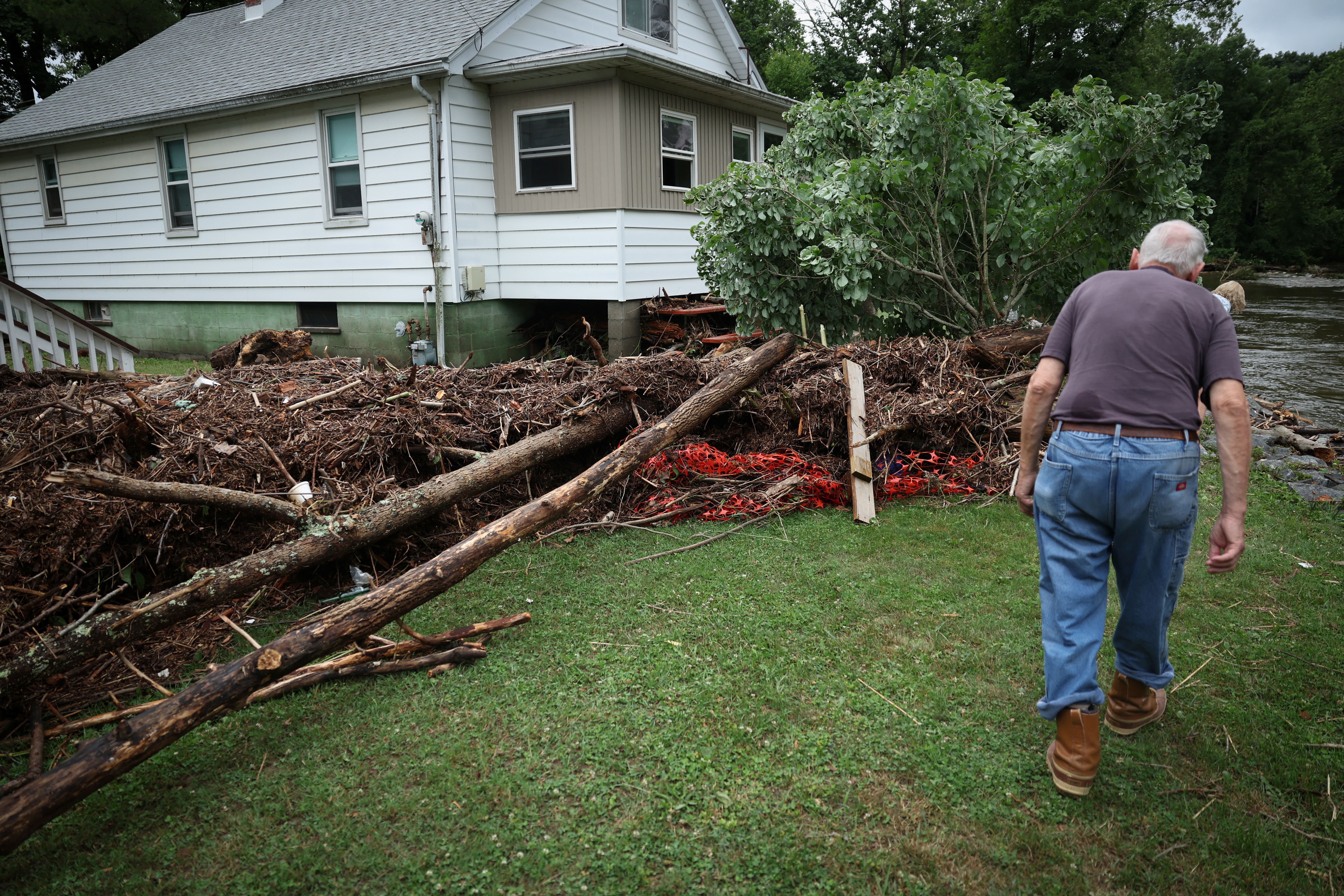 Richard Byers looks over debris outside his home from overnight flooding along Cedar Pond Brook in Stony Point, New York, U.S., July 10, 2023. REUTERS/Mike Segar