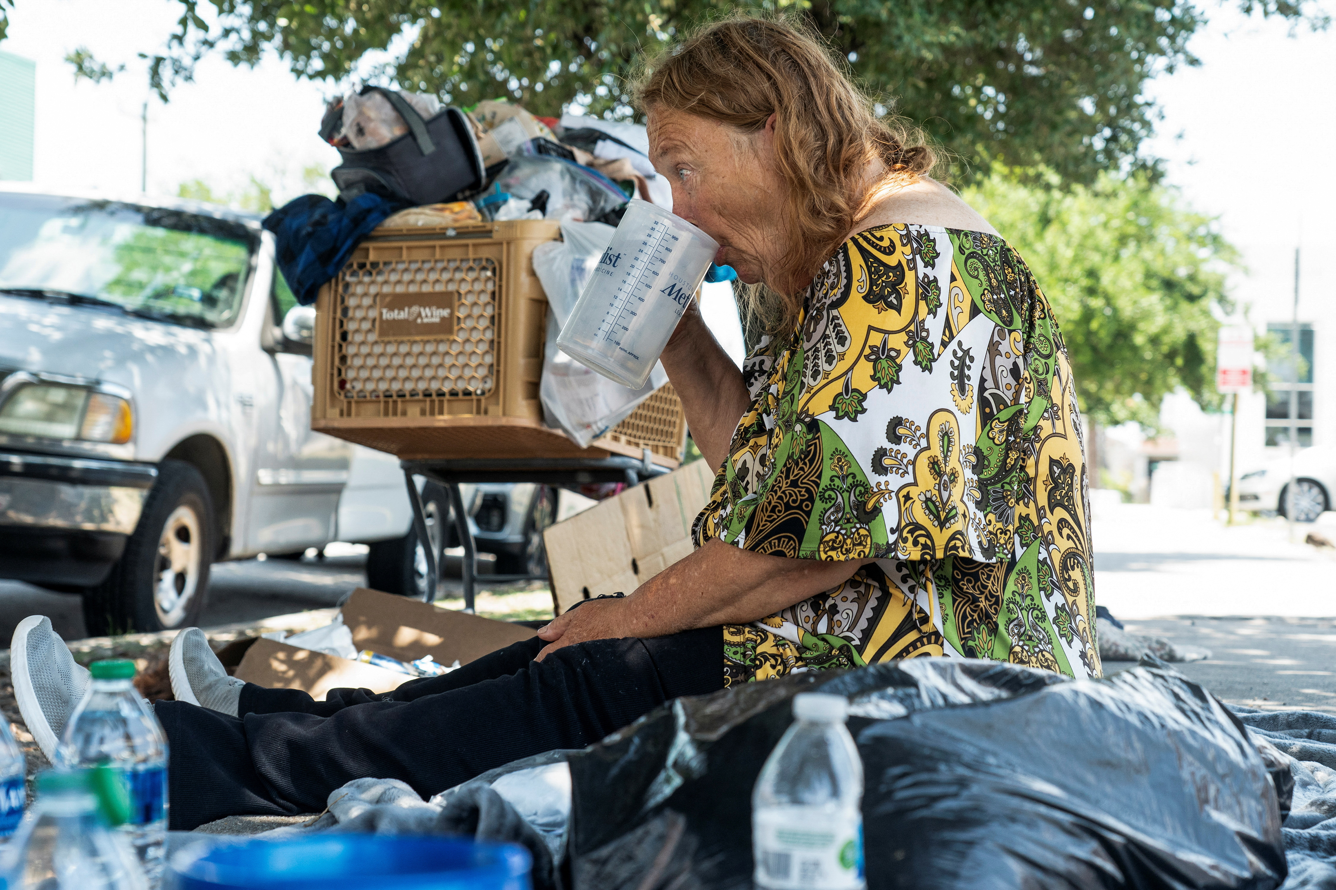 Elizabeth, a homeless woman, drinks water during hot weather in Houston, Texas, U.S. June 28, 2023. REUTERS/Go Nakamura