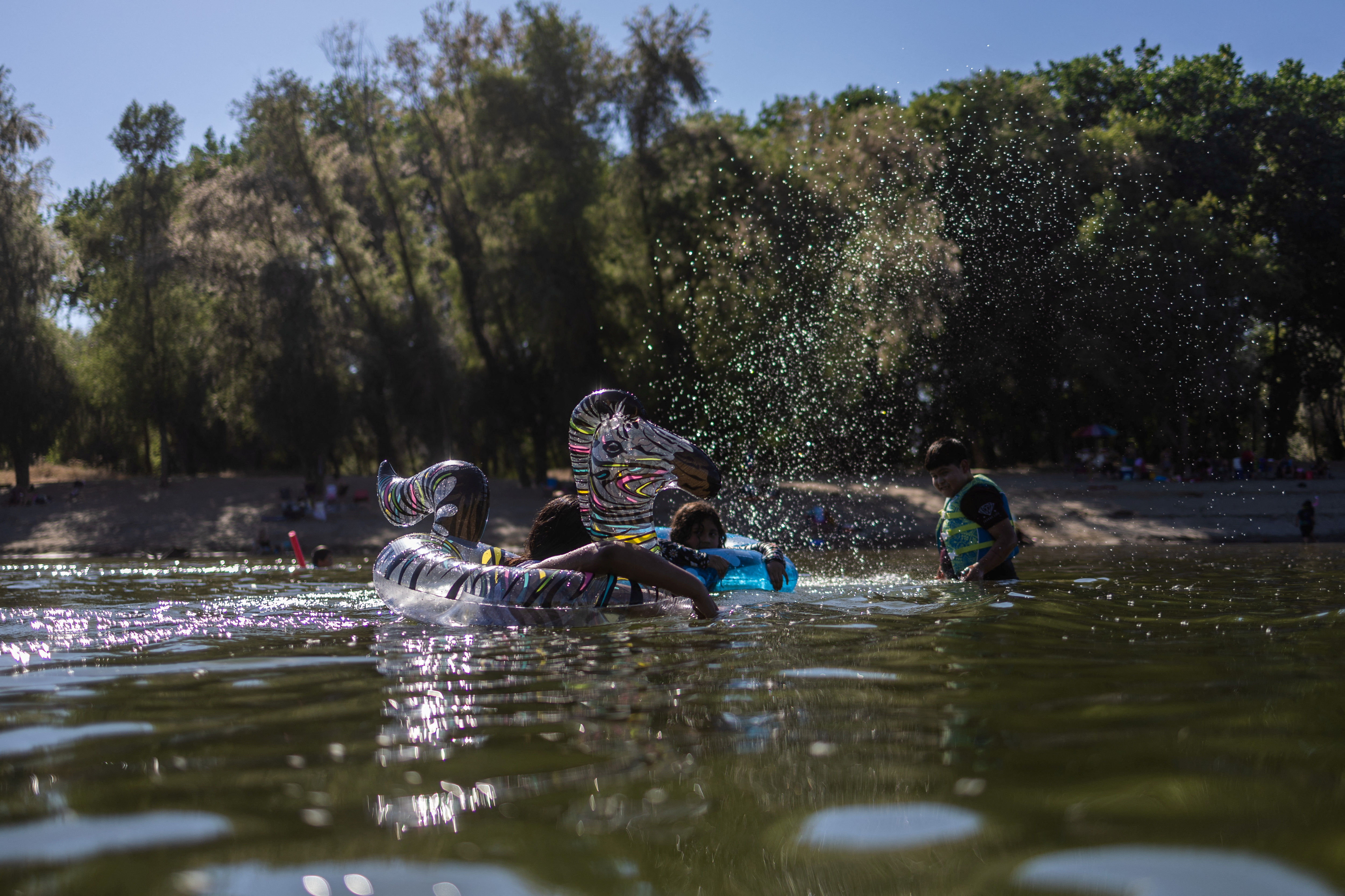 Children refresh themselves at the Feather River, as the temperature rises over 100 degrees Fahrenheit (38 Celsius), in Yuba City, California, U.S., June 30, 2023. REUTERS/Carlos Barria