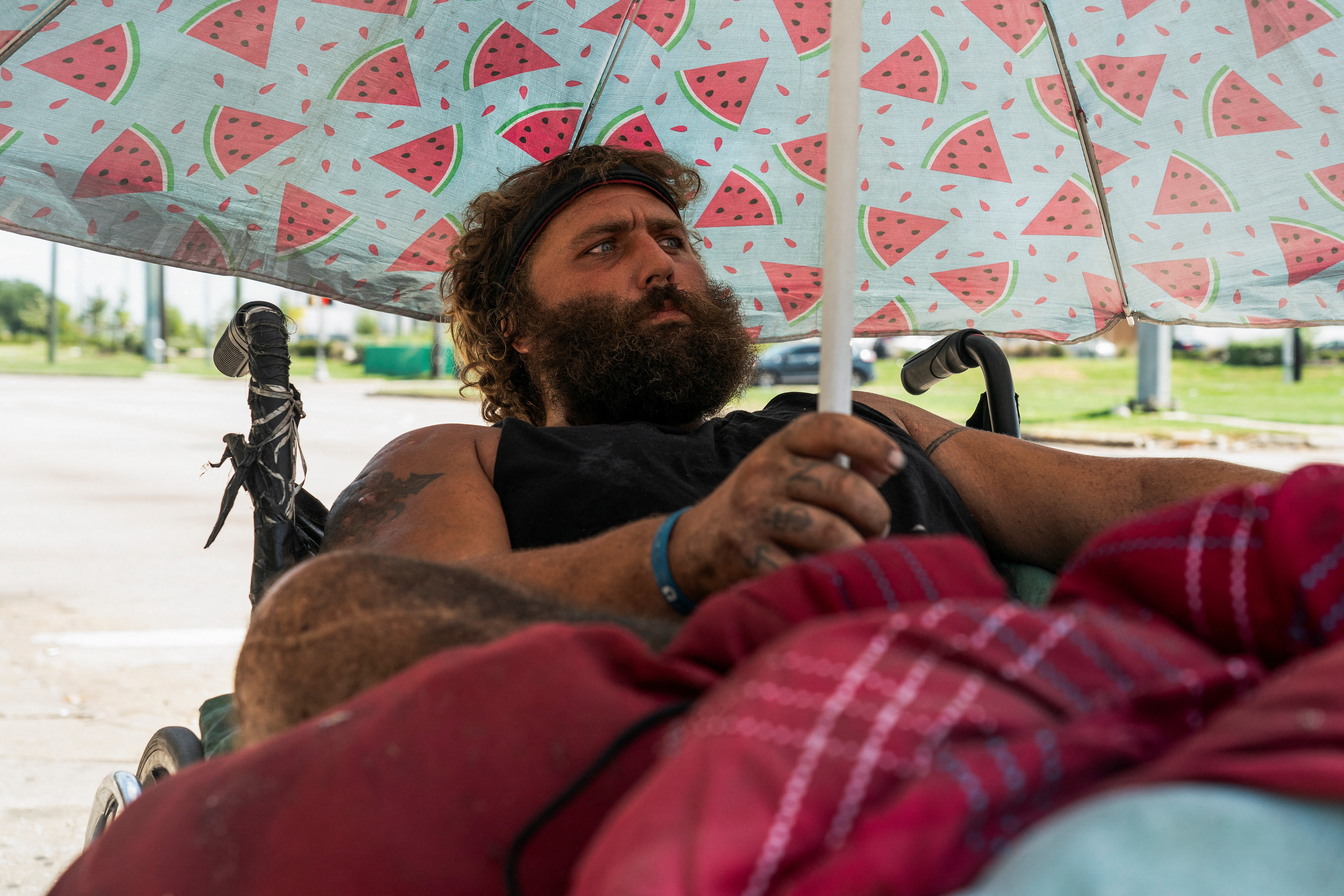 Tony, a homeless man, sits under his umbrella to avoid sun light during hot weather in Houston, Texas, U.S. June 28, 2023. REUTERS/Go Nakamura