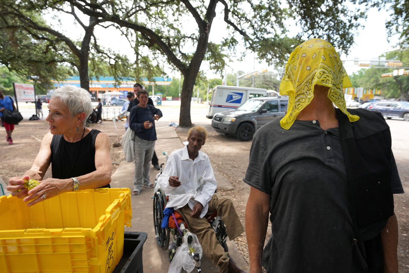 Diana Holloway, Community Engagement Coordinator at Sonrise Homeless Navigation Center, gives ice cold bandanas to Joe Mullins and other people experiencing homelessness during a heat advisory with temperatures expected to top 100 degrees F (37 degrees C) in Austin, Texas, U.S. July 11, 2023. Jay Janner/USA Today Network via REUTERS