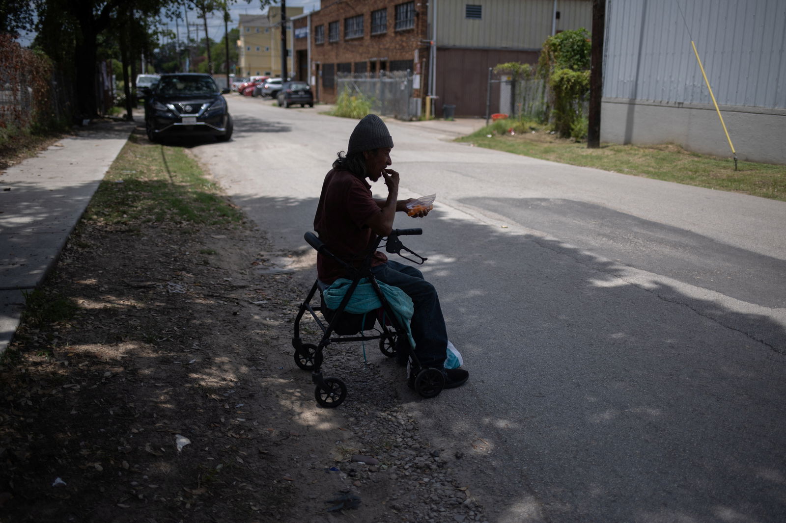 Oscar Martinez, originally from Honduras, has a snack under a tree outside of his residence during hot weather in Houston, Texas, U.S., July 12, 2023. REUTERS/Adrees Latif