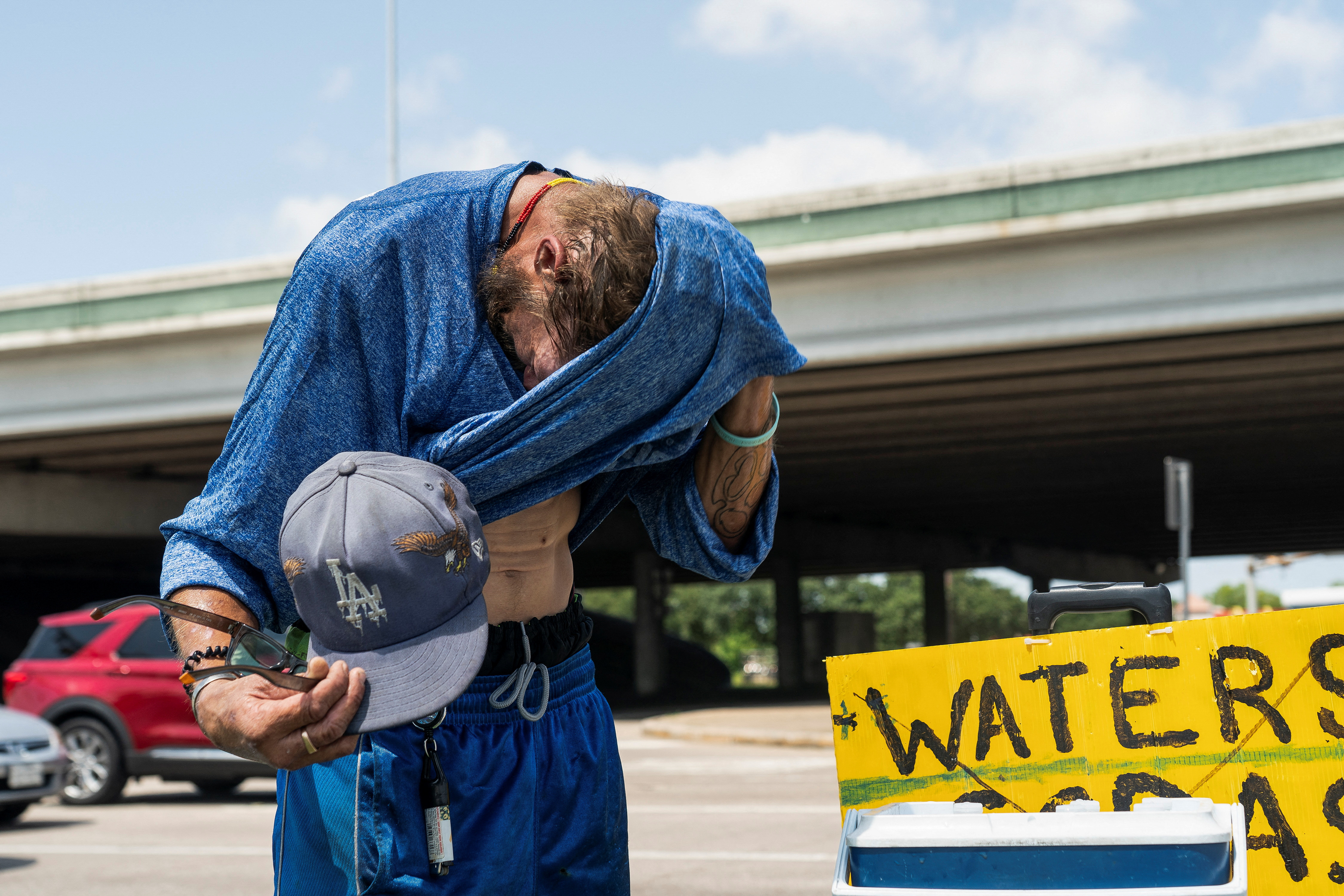 Marc Newman wipes off sweat as he sells cold water to drivers during hot weather in Houston, Texas, U.S. June 28, 2023. REUTERS/Go Nakamura