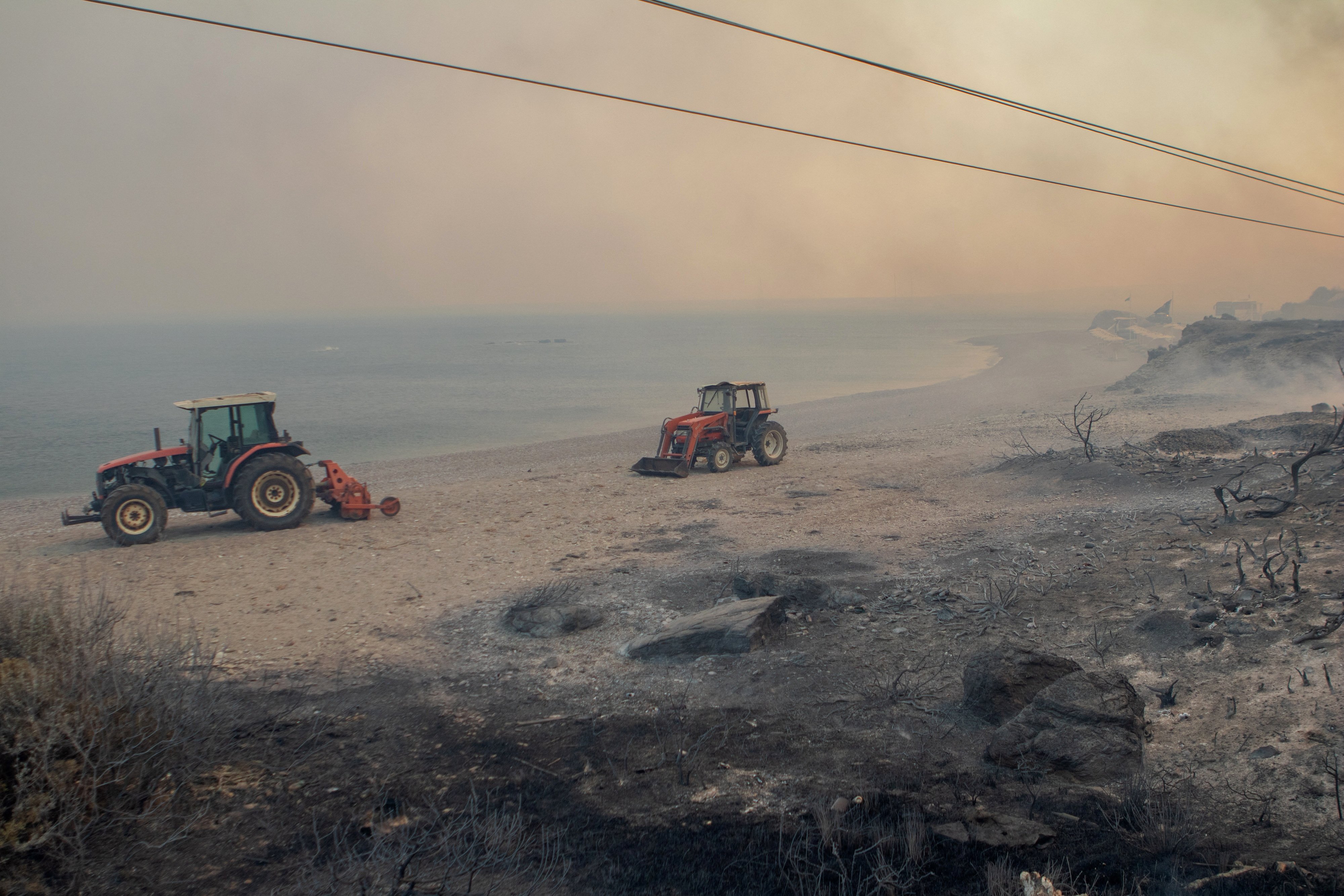 An empty beach is pictured amidst smoke rising from wildfire burning near Lindos, on the island of Rhodes, Greece, July 22, 2023. REUTERS/Lefteris Damianidis