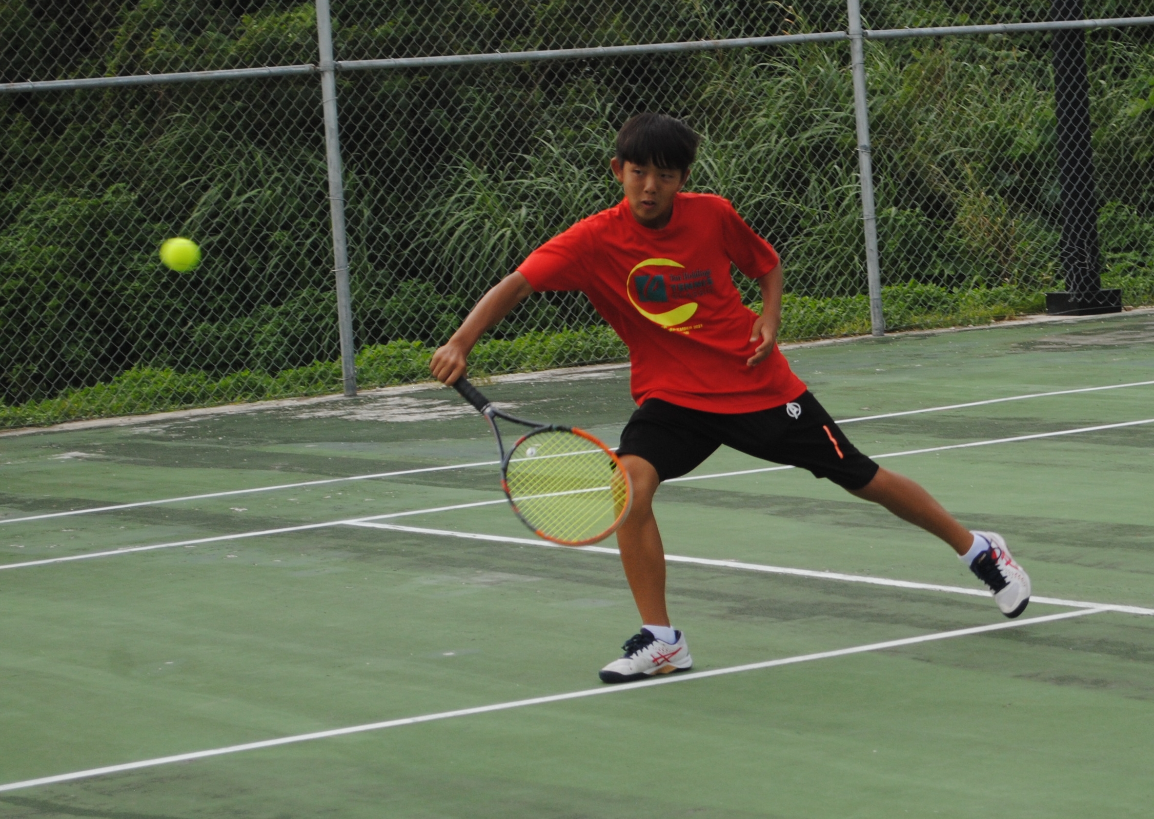 Siwoo Lee extends for the backhand return during a  tennis game at American Memorial Park.