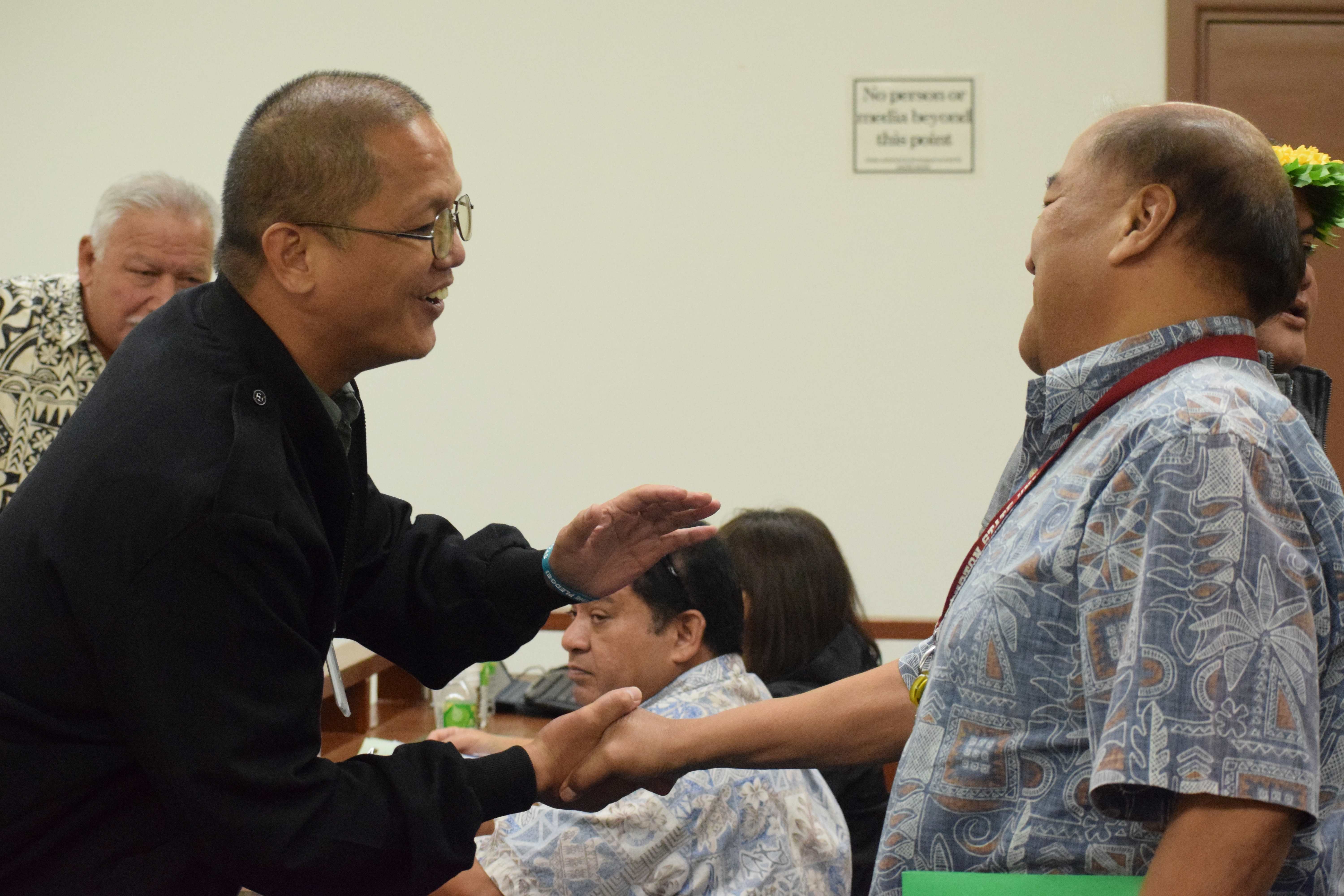 Community Guidance Center Director Kevin Villagomez, rght, shakes hands with Rep. Vincent "Kobre" Aldan during a break from a House session on Friday.