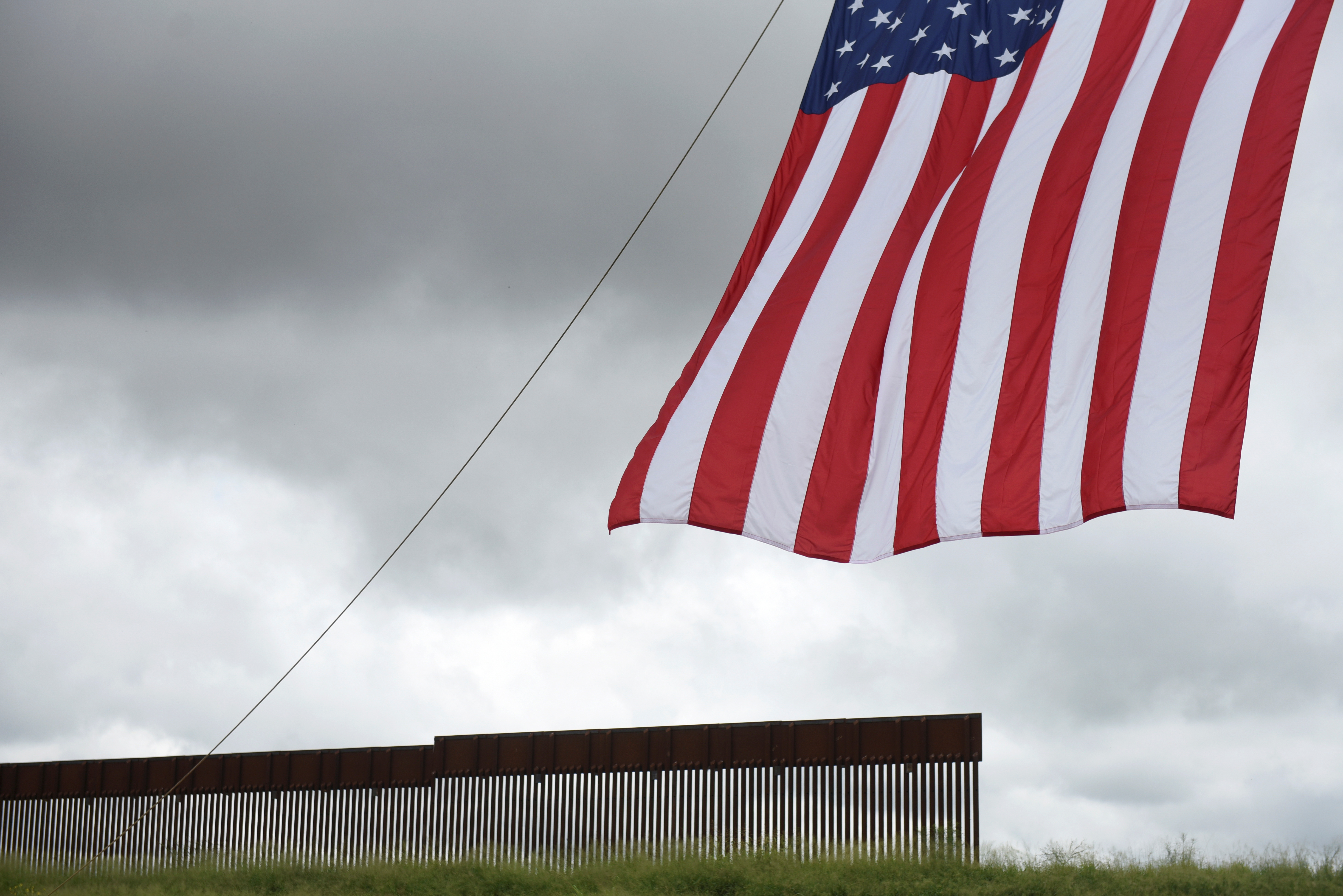 A flag flies in front of a section of the border wall ahead of a visit from former U.S. President Donald Trump and Texas Governor Greg Abbott along the U.S.-Mexico border in Pharr, Texas, U.S. June 30, 2021. REUTERS/Callaghan O'Hare/File Photo