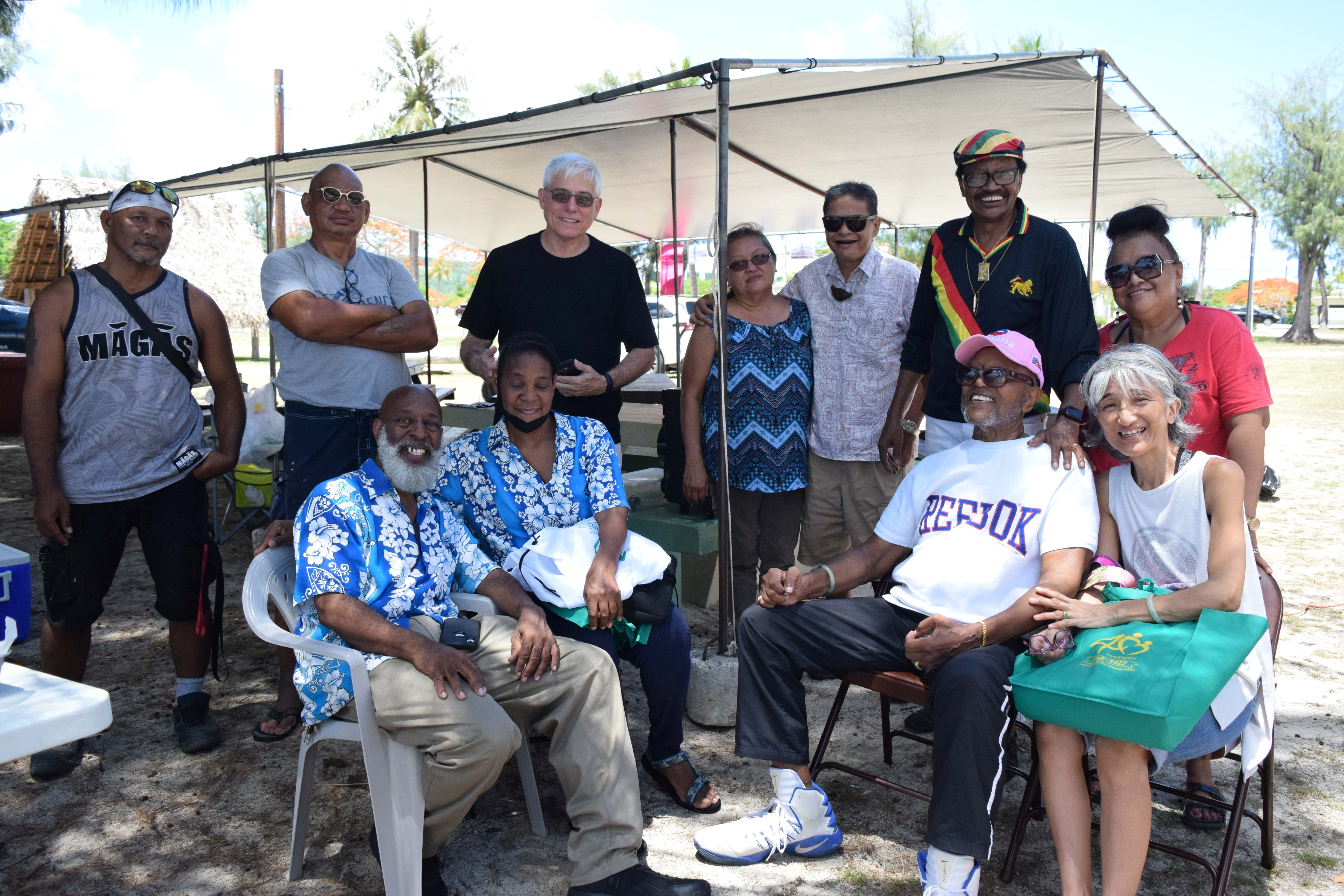 Dr. John Joyner, second right seated, with his wife Yasuko, retired educator Ambrose Bennett, second right back row, and other local residents celebrate Juneteenth in 2022 at the Civic Center beach in Susupe.