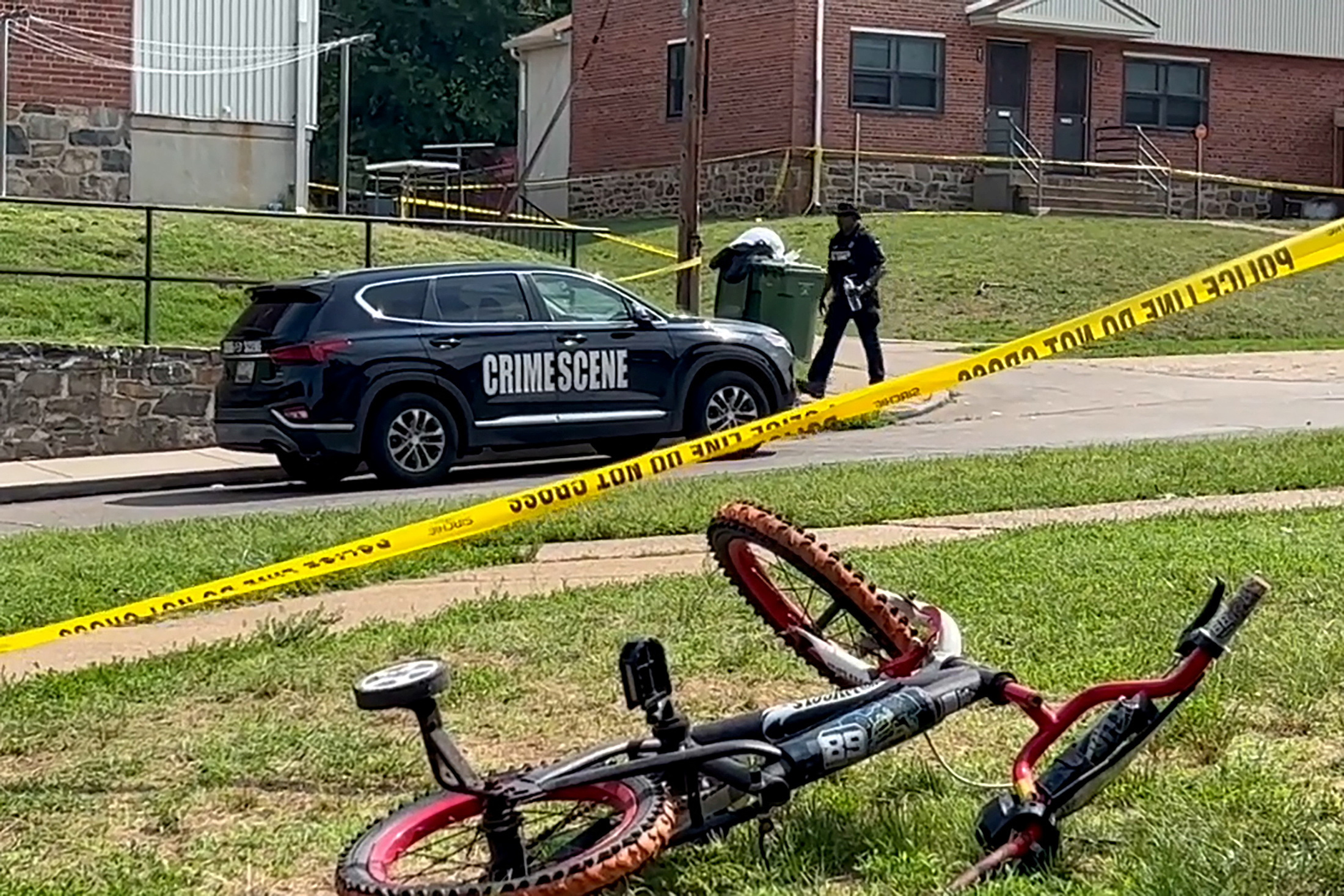 A police officer passes a child's bicycle after a mass shooting at the scene of a Fourth of July holiday weekend block party in Baltimore, Maryland, U.S. July 2, 2023 in a still image from video. REUTERS/Stringer