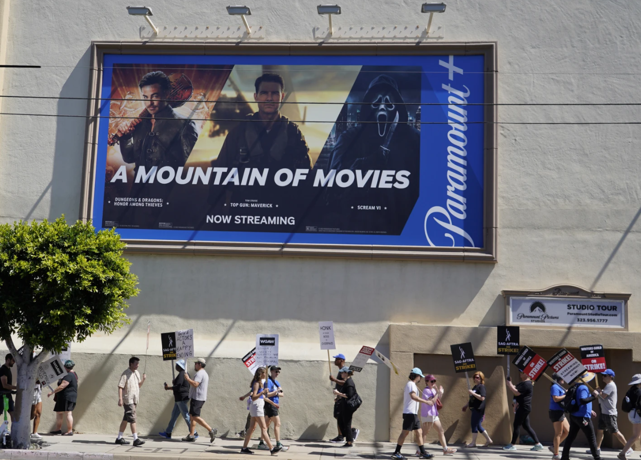 An advertisement for streaming service Paramount+ appears above striking writers and actors at rally outside Paramount studios in Los Angeles on Friday, July 14, 2023.