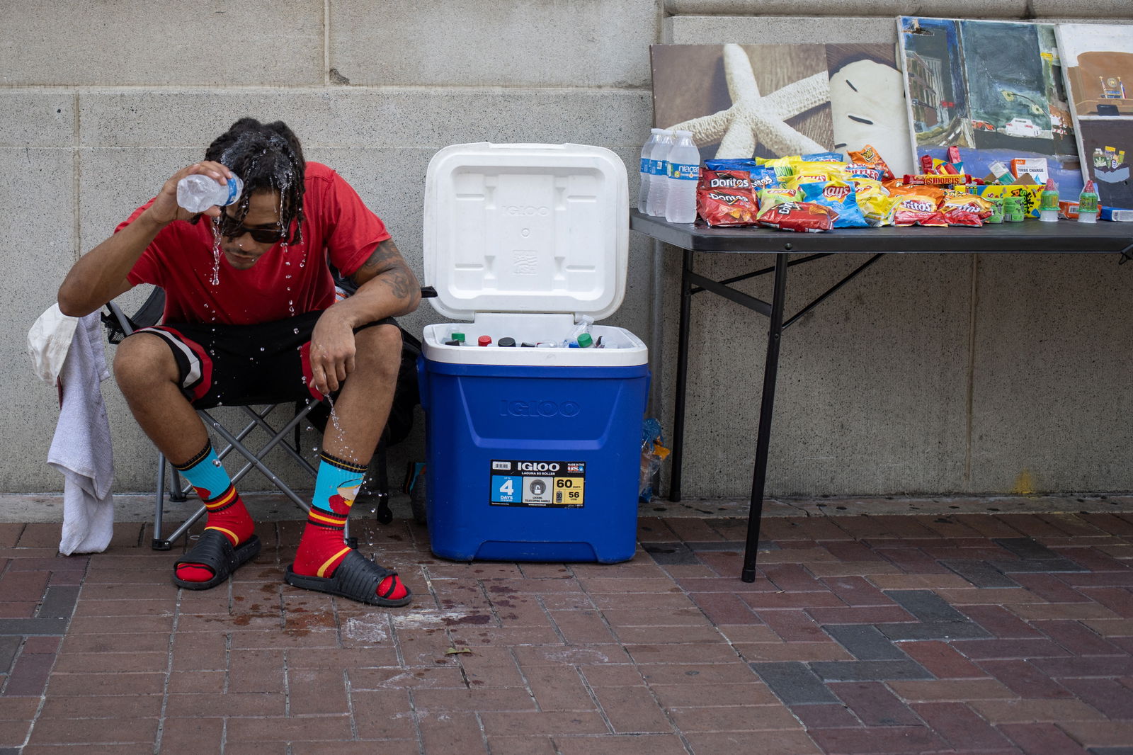 Giovanni Woods pours water over his head to cool down while selling refreshments along a street corner during hot weather in Houston, Texas, U.S., July 12, 2023. REUTERS/Adrees Latif
