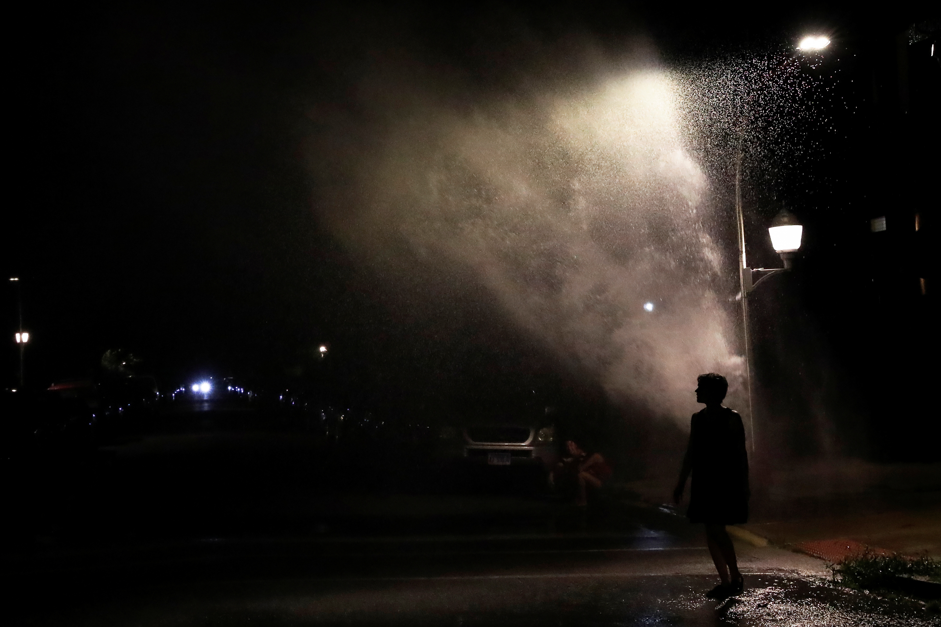 A woman is seen in silhouette under an opened fire hydrant during hot weather in Chicago, Illinois, U.S., July 26, 2020. REUTERS/Shannon Stapleton
