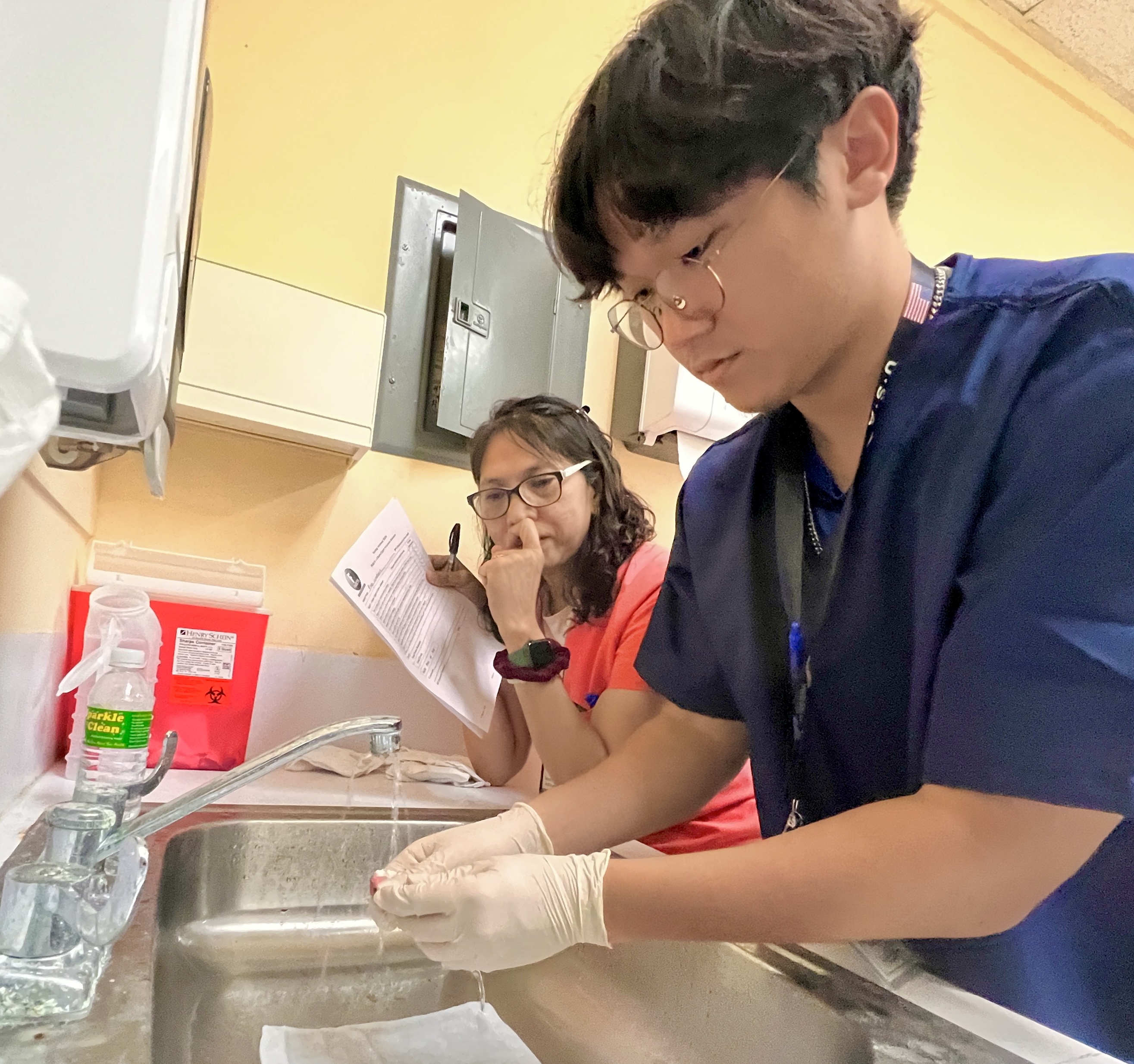 As part of their patient-care training, student Xinwen Jin demonstrates how dentures are cleaned while his nursing instructor Vivian Concepcion looks on.