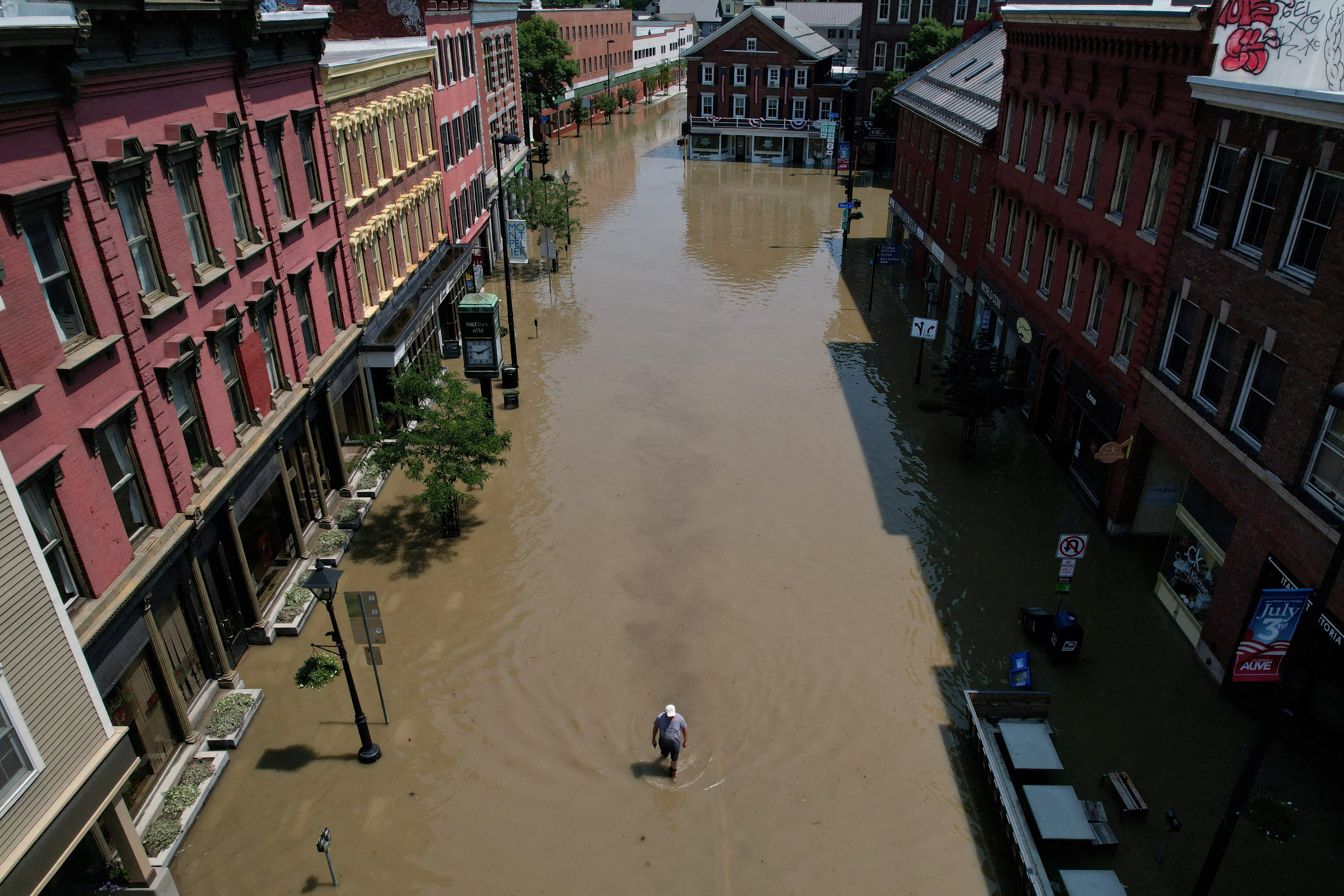 A man walks down street flooded by recent rain storms in Montpelier, Vermont, U.S., July 11, 2023. REUTERS/Brian Snyder/File Photo