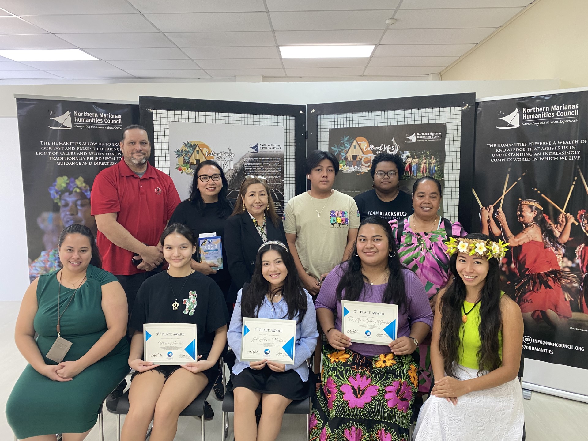First row, front row, from left: Northern Marianas Humanities Council Vice Chair Gretchen Smith, students Brissa Hunter, Jill Mallari and Dryllynne Joseph, council board member Marjorie Daria. Back row: the family members of the winners.