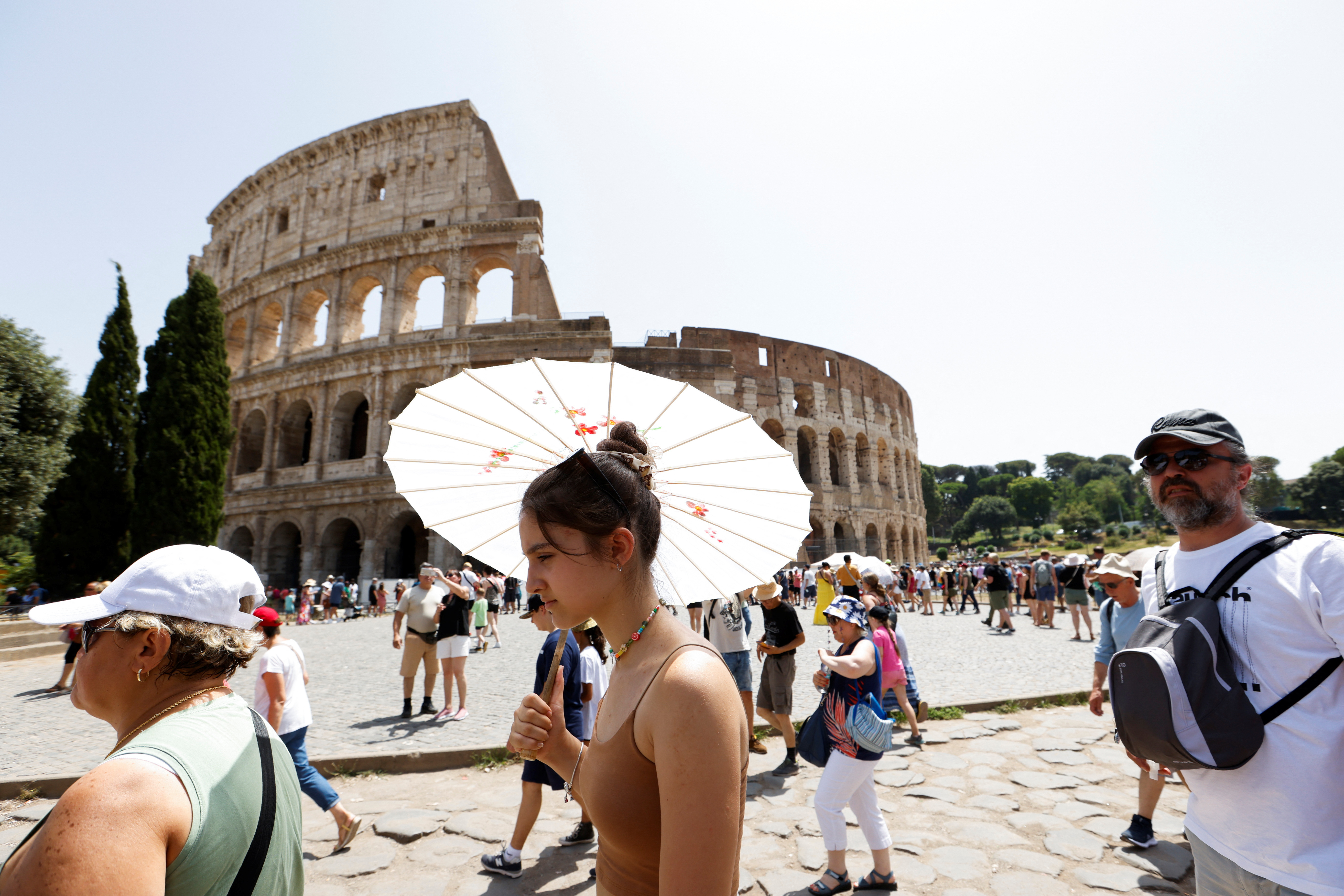 People walk near the Colosseum during a heat wave across Italy as temperatures are expected to rise further in the coming days, in Rome, Italy July 17, 2023. REUTERS/Remo Casilli