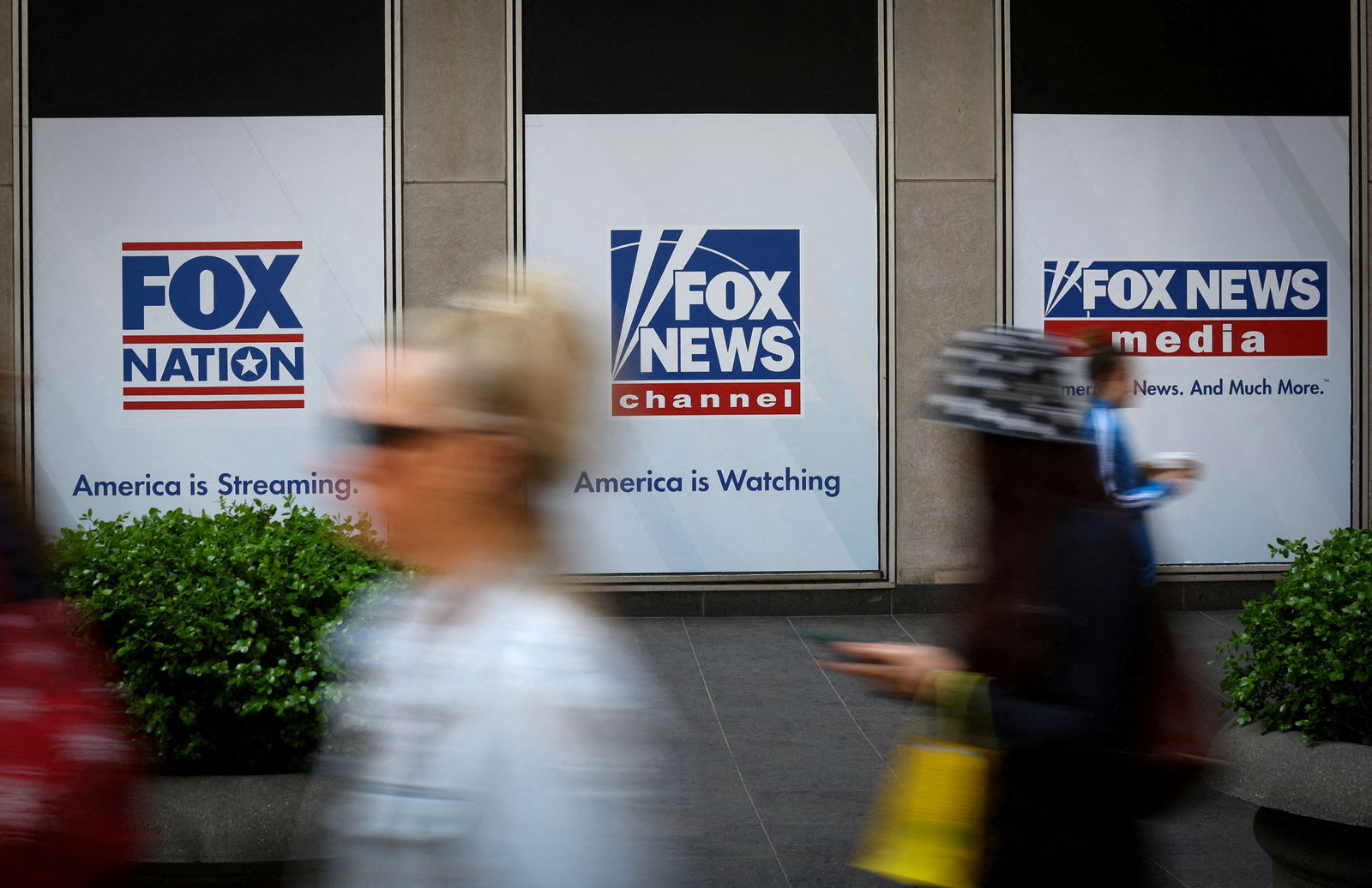 People walk past Fox News posters on the exterior of the News Corporation and Fox News headquarters building in Manhattan in New York City, New York, U.S., April 24, 2023. REUTERS/Mike Segar/File Photo